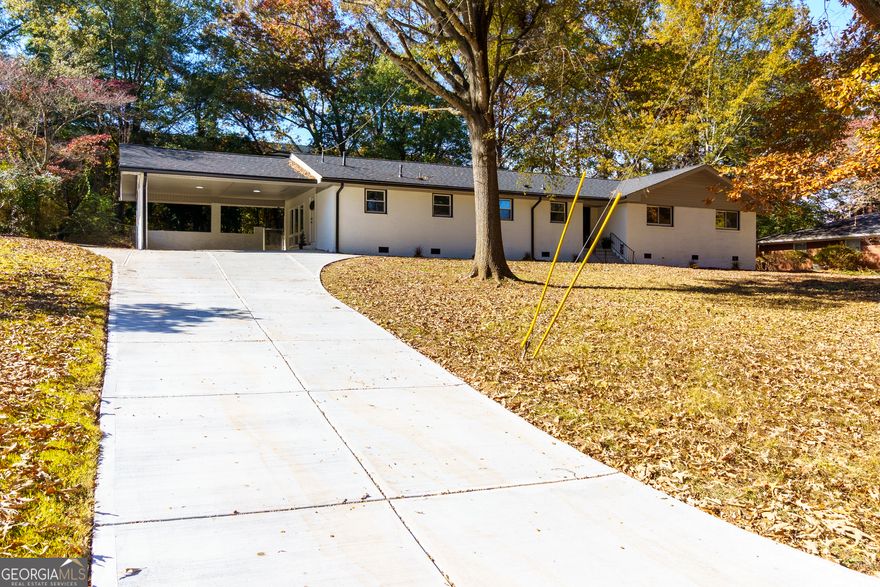 Welcome to this beautifully renovated all-brick ranch situated on a spacious lot with a large front and backyard, dual driveways, and exceptional outdoor potential. One driveway leads to the covered 2-car carport, while the second provides access to additional parking and a workshop, perfect for projects, storage, or extra vehicles. Step inside to an inviting open-concept floor plan featuring the family room, dining area, and kitchen. The family room showcases a stunning marbled accent wall with fireplace, creating a sleek, modern, and elegant focal point. The dining area sits seamlessly between the family room and kitchen, offering the perfect space for entertaining with direct access to the back patio. The chef inspired kitchen is a true showstopper with white cabinetry, granite countertops, abundant storage and prep space, new stainless steel appliances including a double oven, pantry, and a center island with breakfast bar seating. Just off the kitchen, an oversized laundry room provides additional pantry/storage space for maximum convenience.  The primary suite is expansive and features a panoramic window overlooking the backyard, a sitting area, walk in closet, and a fully updated ensuite bath complete with granite countertops, double sink vanity, and a large tiled shower. Two additional bedrooms are generously sized and share an updated full bath with a shower/tub combo. A fourth bedroom offers ideal guest accommodations with its own private ensuite bathroom featuring a newly remodeled tiled shower.  Outside, enjoy a wonderful backyard with a private tree lined view, a large patio perfect for outdoor gatherings, and a separate workshop that offers endless potential; use it for storage, hobbies, or finish it out as a man cave, she shed, or studio. This fully renovated ranch offers modern elegance, functional spaces, and exceptional versatility both inside and out. Don't miss this move-in-ready gem!   Highlights Include: updated flooring, new, neutral paint throughout, renovated bathrooms, updated kitchen, high end finishes throughout, updated appliances, fresh exterior paint, and much more!
