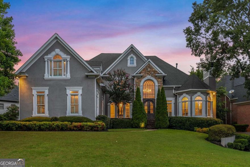 If you're looking for the ideal "home for the holidays," this is it! Situated near the end of a tree-lined culdesac street in the private, guard-gated country club community of St Ives, is this stately home. The mature landscaping and stunning curb appeal of the hardcoat stucco and stone exterior greet you upon arrival. Enter through the custom arched iron front doors and into soaring ceilings, abundant natural light, gleaming hardwood floors, extensive custom millwork and designer touches throughout. The thoughtful floorplan seamlessly blends formal and casual spaces. Pass by the vaulted fireside room in the front of the home that's ideal for a large office, formal living room, music room or library. The two-story great room features a second fireplace, custom built-ins with shiplap accents and a wall of windows that overlooks your private backyard oasis. The renovated kitchen with a Wolf/SubZero professional appliance suite and quartzite countertops is the perfect spot for cooking holiday meals. The large island is ideal for serving and conversation as it flows seamlessly into the vaulted fireside keeping room and oversized breakfast area with seating for 6. You'll love the convenient butler's pantry/wet bar for serving festive beverages. A large walk-in pantry completes the kitchen area and allows for ample food storage! One-level living is achievable in this home with a master suite on the main level that's highlighted by jaw-dropping 18' trayed ceilings, dual custom walk-in closets and a modern, spa-like ensuite bathroom with oversized individual vanities, a large shower and separate soaking tub. Completing this level is a formal dining room, custom mudroom off the 'friends entrance,' large light-filled laundry room and beautiful powder room. The upper level of this home, reached by one of two staircases, includes three expansive guest bedrooms, two with a shared bathroom and one with a private ensuite. All bedrooms feature elevated ceilings with custom millwork details - something you rarely find in most homes. The sprawling and thoughtfully renovated basement is the perfect spot for casual entertaining. Football, anyone?! You'll love the large wet bar with island seating for 8, casual media room, expansive game room, office/craft room with custom built-ins, home gym with steam shower, guest bedroom with ensuite bath plus a secondary full bath for additional guests. There is also a large storage room for all of your overflow items (and holiday decor!). In addition to the aforementioned outstanding features, this home has new windows throughout, a new hot water heater, a new pool pump and three HVAC systems that are less than 5-years-old. The property is situated on one of the most quiet, sought-after streets in the neighborhood with direct access to the swim/tennis amenities. There is optional membership to St Ives Country Club where you can enjoy a stunning European-inspired clubhouse with multiple restaurants, a beautiful pool with cabana restaurant and bar, the most active tennis community in Johns Creek with 16 tennis & 4 pickleball courts, a sprawling playground for the kids, a basketball court and, of course, an award-winning private golf course designed by Tom Fazio. Zoned for top-rated public schools in Johns Creek and conveniently located near coveted area private schools. Johns Creek was recently voted the #1 city to live in the state of Georgia and a top city in the United States. This property is sure to check all of the "boxes" on your holiday home wish list!