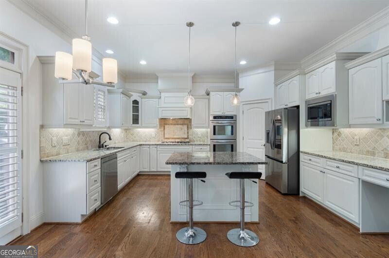 Gorgeous "Builder's Home" in Chastain Ridge Neighborhood in East Cobb. Nestled in a quiet cul de sac, this home boasts an impressive open floorplan with soaring coffered ceilings. Light and bright,updated kitchen looks out to huge fireside den. Huge windows allow for natural light that flows throughout the home. This home has tons of upgrades like updated lighting, custom plantation shutters on all windows, hardwoods on all floors throughout, and a terrace level that will knock your socks off. Upstairs you'll find spacious bedrooms with walk in closets for tons of storage space.Primary suite has vaulted ceilings, huge bath with walk in closet and double vanities. Bedroom or office on main floor. Walk out from eat-in kitchen with island to beautiful deck overlooking the lush green backyard with playset, perfect for your morning cup of coffee. You'll find the terrace level of your dreams with high ceilings and a bar with icemaker and TV overlooking another fireside den and open to screened porch. Truly a place for everything you could ever need. Two car garage includes storage shelving perfect for keeping tidy. Hot location close to restaurants, shopping, parks and more! Don't miss this special home!