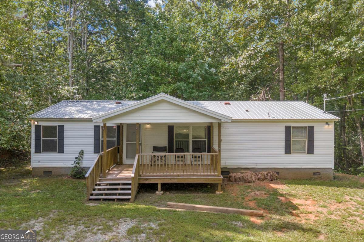 Nestled in the foothills of the North Georgia mountains, this well-kept 3 bedroom, 2 bath manufactured home rests on 1.1 acres with a permanent foundation in northern Dawson County and is being offered for the first time by the original family. The home welcomes you with a large covered front porch, the perfect spot for morning coffee or unwinding in the evening. Inside, you'll appreciate the desirable open-concept design with a split-bedroom layout and a versatile bonus room that could serve as an office, dining room, playroom, rec room, or den. The spacious eat-in kitchen includes pantry storage and offers the option to add a center island or coffee bar for extra workspace and seating. The master suite features a double vanity, tiled shower/tub combo, walk-in closet, and tile flooring. Most of the interior has fresh paint, with laminate flooring throughout and tile in the bathrooms. The exterior is low-maintenance with vinyl siding and a durable metal roof. The home has central heat and air, along with a propane wall heater for backup. The land extends to the top of the hill behind the home, giving you plenty of space to fence in, ride ATVs, or explore. For outdoor enthusiasts, the location couldn't be better-just 15 minutes from Amicalola Falls State Park, the Amicalola River for trout fishing, tubing, and kayaking, Dawson Forest WMA for hunting, and Jakes/Bull Mountain for biking and horseback riding. Titles have already been retired, this home could be your perfect mountain retreat or full-time residence.