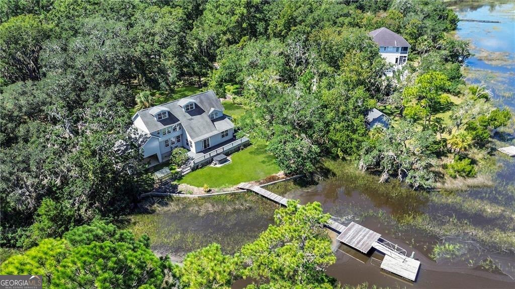 Experience the epitome of coastal living with this private 1.22-acre retreat, a rare gem offering stunning marsh and tidal creek views that promise a spectacular start to every day. Nestled among magnificent Live Oaks, this home is thoughtfully designed to immerse you in the natural beauty that surrounds it. The open-concept layout seamlessly connects the main living areas, with the kitchen, dining, and great room all offering spectacular views. Step out onto the expansive deck, perfect for entertaining, or unwind in the hot tub as you soak in the peaceful scenery. The home's functional design includes a convenient first-floor bedroom and a full bath, ideal for guests or multi-generational living. Upstairs, you'll find two additional guest rooms with a shared bath, along with a generous primary suite featuring a huge walk-in closet and more of those incredible views. An unfinished third-floor bonus room provides endless potential or use as floored attic storage. The outdoor space is a true paradise for nature lovers. The property includes a private dock perfect for fishing, lounging, or launching your kayak, canoe, or small boat at high tide. Additional features include a chicken coop and a storage building. Great opportunity for waterfront lifestyle. Termite Bond with Allied Pest. Roof 13 years, Water Heater 12 years. Easy to show!