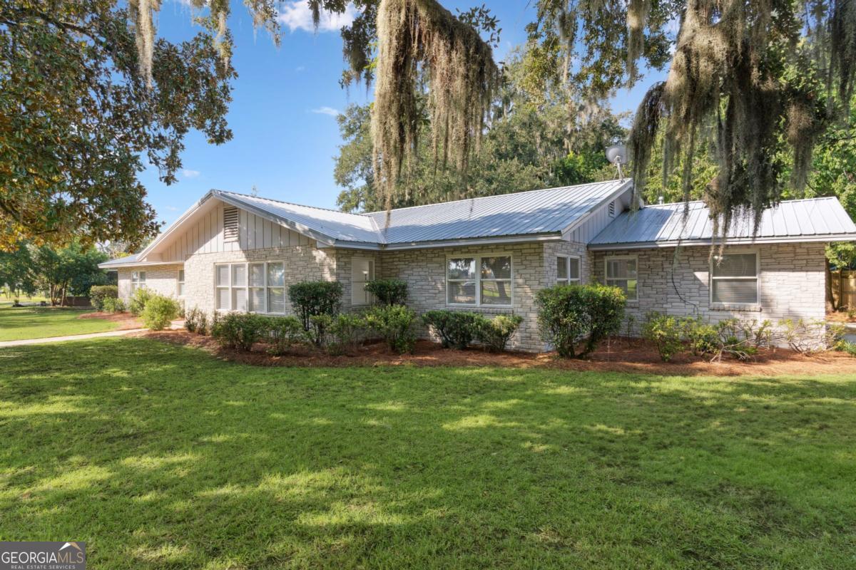 Beautifully renovated and thoughtfully designed, this home combines elegance with everyday comfort. The floor plan features formal dining and living rooms, a welcoming den with fireplace, and a large kitchen with Corian countertops and breakfast area. The fourth bedroom near the front entry could also be used as an office or flex space, while the three additional bedrooms are impressively spacious. The primary suite offers a private ensuite bath, and the secondary bedrooms share a convenient Jack-and-Jill. Step outside to a huge screened back porch overlooking the fenced yard. Enjoy the outdoors from the huge screened back porch overlooking the fenced backyard with storage building. This home features a Geothermal HVAC system - A geothermal HVAC system uses the steady temperature of the ground to heat and cool the home more efficiently than traditional systems. The pump house contains the pump, replaced in 2024, for the geothermal system (drinking water is supplied thru Public Water), with underground pipes running from the pump to the home's HVAC system. This home is equipped with a three-phase electrical system, a feature rarely found in residential properties. (Unlike standard single-phase power, three-phase service provides a more consistent and efficient flow of electricity, making it ideal for running larger appliances, workshop equipment, or future expansions with ease.) HVAC unit appears newer, Two Water Heaters (one in attic is electric. age 8/2020. One in carport is Gas. Age 6/2025). Metal Roof is 5-7 years old. 1425 Lanier Blvd is located in the historical Windsor Park neighborhood of Brunswick, Georgia. Directly across the street from Howard Coffin Recreational Park and just steps from Overlook Park with its fishing pier and views of the marsh, this home enjoys a prime location for recreation and outdoor enjoyment. It sits at the gateway to the St. Simons Island Causeway and, just over the Sidney Lanier Bridge, offers quick access to the Jekyll Island Causeway. The property is also moments from Historic Downtown Brunswick, where local shops, dining, and cultural attractions bring the city's history and charm to life. Seller is licensed realtor. Easy to show!