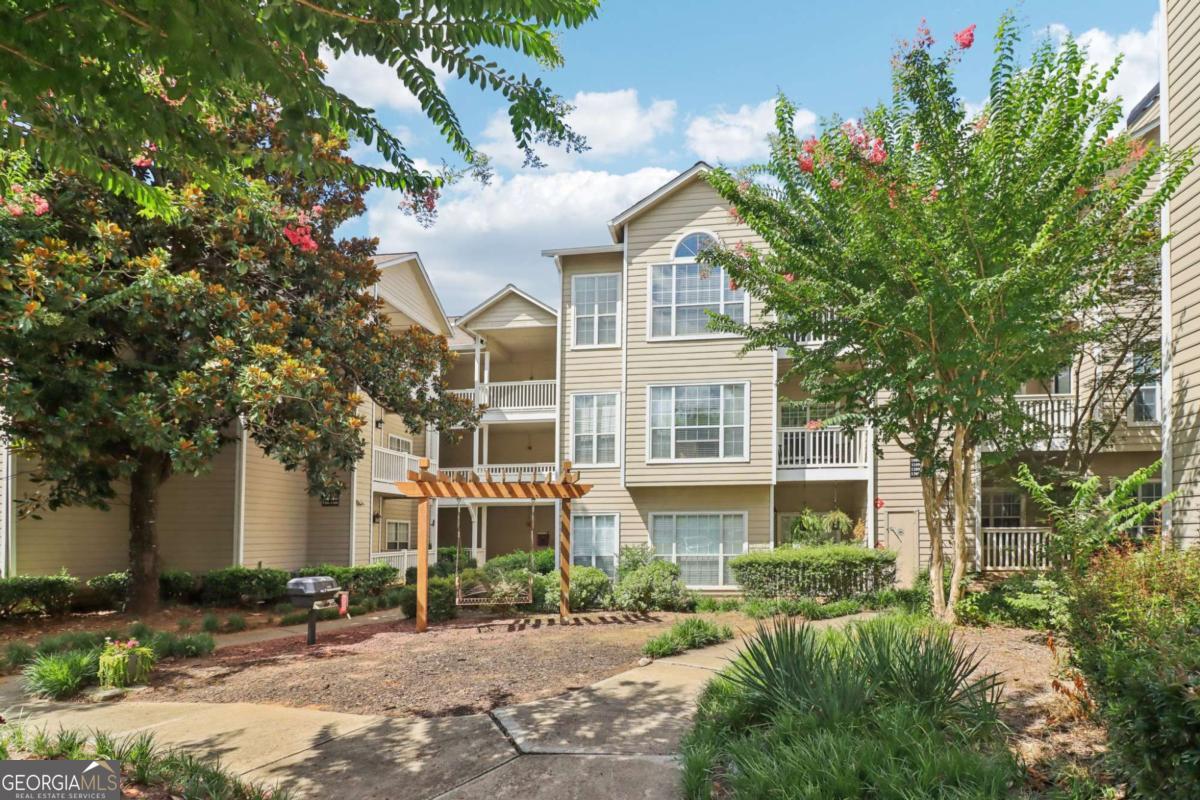 Bright and Spacious End-Unit Condo in Gated Community with Resort-Style Amenities! Welcome to this lovely end-unit condo filled with natural light and an open, airy feel. Step inside to discover beautiful, easy-to-maintain laminate wood floors throughout the spacious living area with soaring ceilings. A separate sunroom offers the perfect spot for a home office, reading nook, or cozy retreat. The open-concept layout includes a dedicated dining area and a well-appointed kitchen featuring granite countertops, stainless steel appliances, a breakfast bar, and a nearby laundry room for added convenience. The spacious bedroom includes a large walk-in closet with a full bath close by. Enjoy a private balcony which overlooks a serene, park-like setting complete with a swing and grill surrounded by blooming crepe myrtle and magnolia trees. There's even a private storage closet on the balcony for your extra items! Located in a secure, gated community, this home offers access to exceptional amenities, including a pool with an outdoor kitchen and grilling area, tennis courts, fitness center, community garden plots, and a convenient car wash station. Recent upgrades include a brand-new HVAC system (2024), new water heater (2023), and Nest thermostat, offering modern comfort and efficiency. Perfectly located near the Chattahoochee River and just a short drive to Truist Park, this condo offers both peaceful living and unbeatable convenience. Book your tour today!
