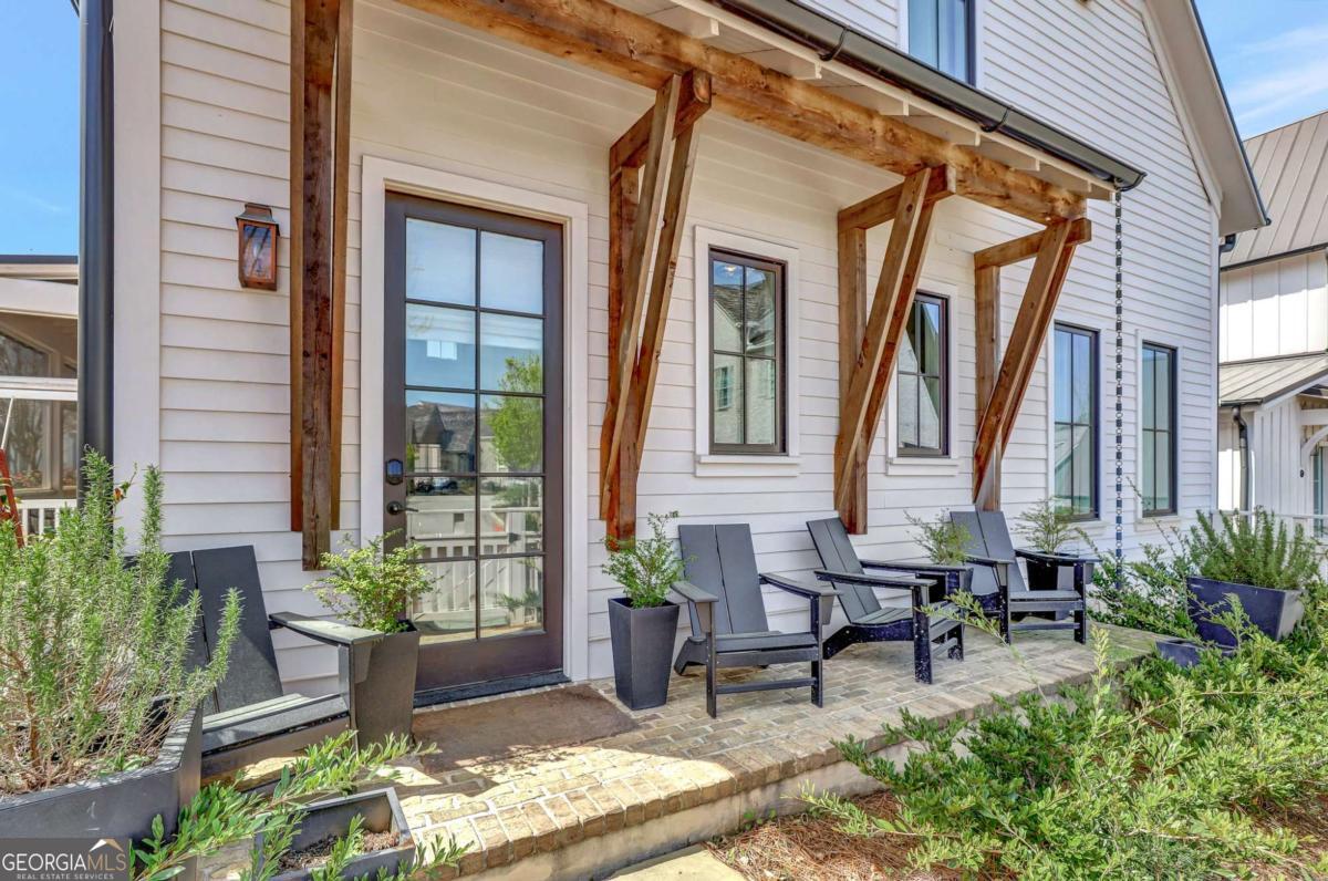 Discover this charming home situated in the heart of the Mado Hamlet of Serenbe, featuring a welcoming wrap-around rocking chair porch perfect for relaxation and entertaining. Inside, the home offers a bright, open floor plan with a primary suite and a guest bedroom conveniently located on the main level. Upstairs you'll find a third bedroom alongside a flexible loft space - ideal as a fourth bedroom or secondary living area. The home also includes a cozy screened porch and a fenced-in yard, perfect for furry friends to enjoy. Additionally, there's a 2-car parking pad that can easily be converted into a carport for covered parking. Centrally located just a short distance from restaurants, cafes, and boutique shops, it provides direct access to over 20 miles of scenic nature trails with peaceful, protected forest views.