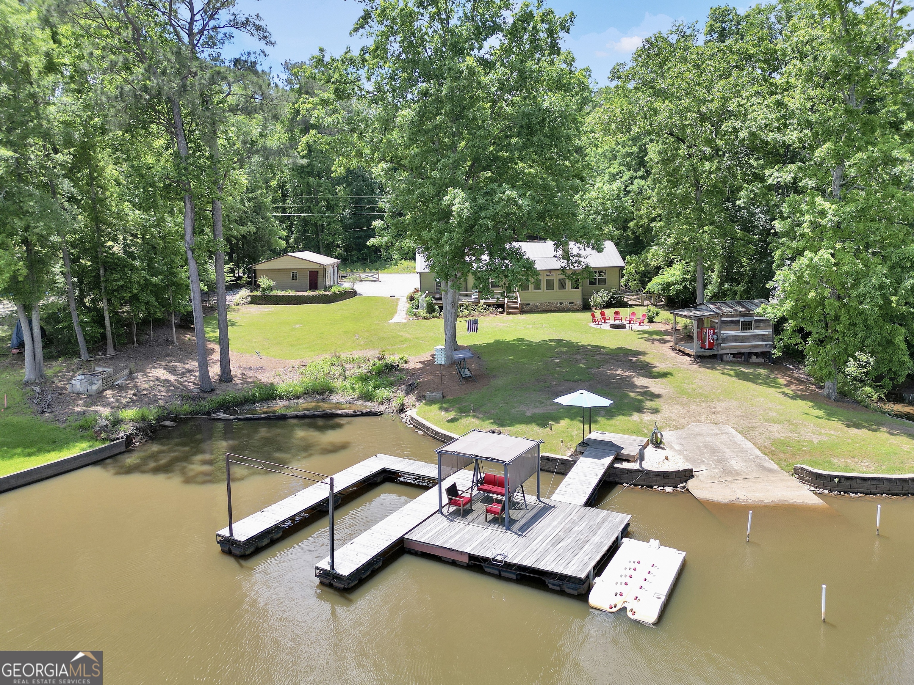 Welcome to this immaculate, custom-built lake home nestled on a DEEDED 0.64-acre lot with everything you need for laid-back, lakeside living. Enjoy your private dock with a single boat slip, a swim dock, a boat ramp, and a recently rebuilt seawall. Everything you need for lakeside fun. Step into lakeside living with this beautiful 4-bedroom, 2-bath home that offers the perfect blend of rustic charm and modern comfort. Inside, you're greeted with a warm, lodge-style atmosphere featuring 9' ceilings, reclaimed wood, metal accents, and high-end luxury vinyl plank flooring throughout. The kitchen is a standout with solid Hickory custom cabinetry, rich granite countertops, and Samsung Smart black stainless appliances. Cozy up in the spacious living area beside the Vermont Castings wood-burning stove or take in lake views from the light-filled entertaining room, ideal as a dining area, game room, or second living space overlooking the cove. The oversized primary suite includes a large walk-in closet and a spa-like bath with a roomy tiled shower. A versatile flex room off the main living area provides options for a second bedroom, office, or bonus game room. Bedrooms 3 and 4 are generously sized and share a Jack & Jill style closet. Outside, you'll find a detached 20x40 two-bay garage with power and workshop space, plus a powered fish shack and a Breeo smokeless fire pit. Perfect for evening gatherings. This home also features dual 200-amp panels, two 40-gallon water heaters, and energy-efficient spray foam insulation to keep utility costs low. This one-of-a-kind lake property offers the perfect balance of comfort, style, and location. Located in one of the area's most desirable spots, you'll love the easy access to the water and peacefull surroundings. Move-in ready and waiting for you to enjoy. Don't miss your chance to own a piece of Jackson Lake paradise!