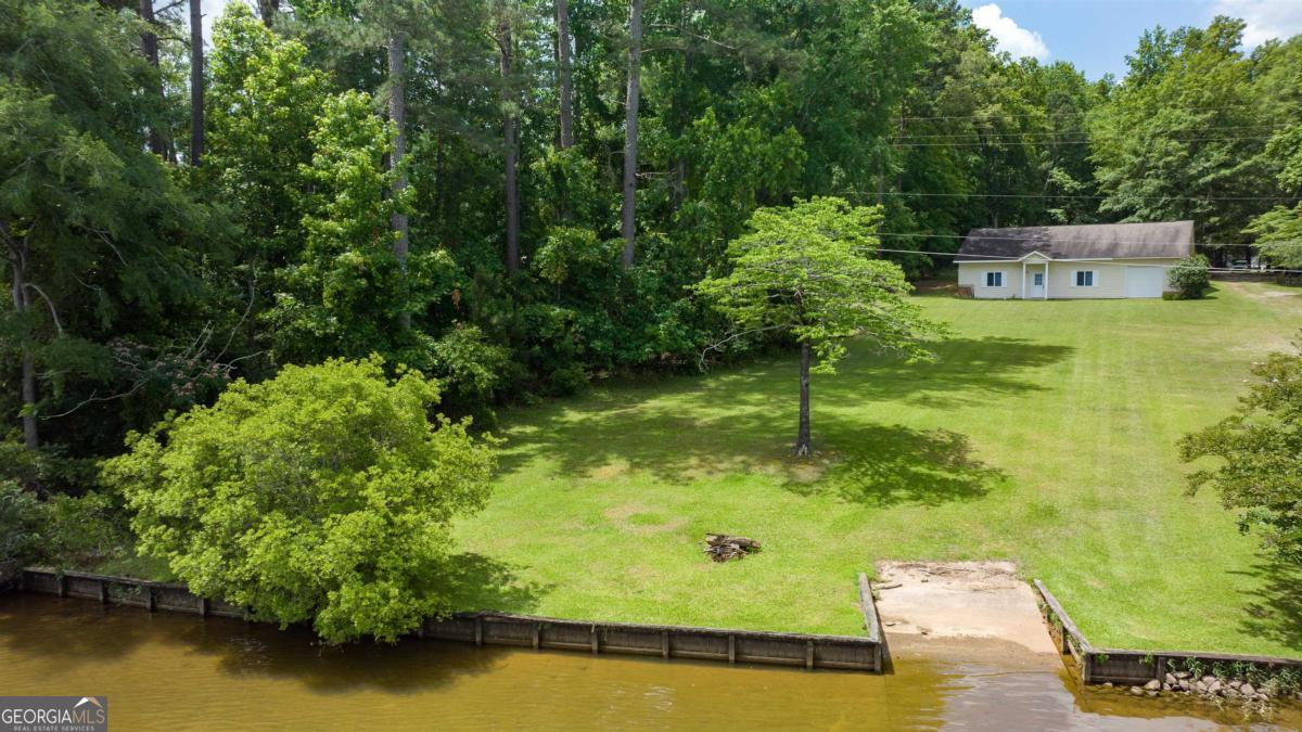 Do not let this LAKEFRONT opportunity pass you by! This 1.28-acre Lake Sinclair FEE SIMPLE lakefront lot is primed for your dream home and includes a 50 amp RV hook up ready for use. With approval for a single-stall boathouse from GA Power, convenient location to Kroger and downtown Milledgeville, GA, and the added perks of a wood sea wall and concrete boat ramp already in place on the property, the groundwork is laid for your lakeside retreat. Plus, utilities ready for hookup, and the existing structure offers over 1560 sq ft of space to customize as a single or two-story dwelling. The foundation is already equipped with a roof, windows, doors, and garage doors, making it easier than ever to bring your vision to life. Immerse yourself in the tranquility of this lake setting, where privacy and outdoor recreation opportunities surround you, from watersports and fishing to leisurely boating excursions.