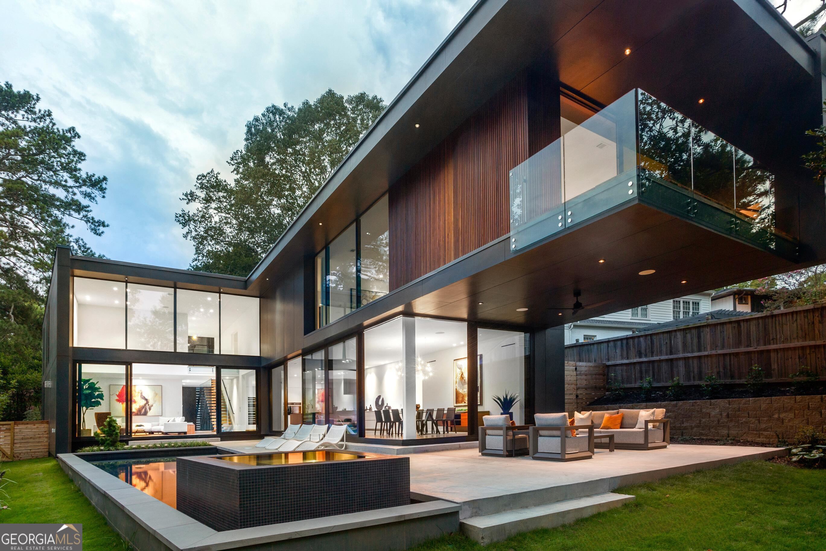 The epitome of modern design, Cantilever House was conceptualized and designed by visionary AIA award-winning architect, Sheila Lee Davies, and built in collaboration with Darby Construction. After a 3-year evolution the home is ready to take its place as one of most architecturally significant modern homes ever built in Atlanta. Nestled in the heart of Morningside, passersby are not privy to the eponymous cantilever design in the rear, as the front facade is consciously restrained to maximize privacy. A curated palette of exterior materials blends seamlessly as polished stucco, ipe slatted wood, and cementitious panels expertly marry together. Guests are graciously greeted by serene exteriors by Brendan Butler Landscape + Design. With an architectural concrete path winding its way to the front entrance, it's easy to miss a 2-car garage masterfully concealed behind a wall of ipe wood slats, an elegant stroke of master craftsmanship. A stunning 10' tall pivot door welcomes you inside revealing a floating stairwell connecting 3 distinct levels of living space. For the ultimate convenience, a private elevator affords easy access to the 6,547 sq ft of space. The double-height Living Room draws you in with soaring glass and is punctuated by a dramatic 6' linear gas fireplace and custom built-ins. Microcement floors seamlessly tie together the living spaces. Imported from Europe, Reynaers window and door systems offer the highest level of energy efficiency, and in spectacular fashion allow entire walls of glass to effortlessly slide open. The Display Kitchen is a study in luxury as custom cabinetry conceals a state-of-the-art appliance package. Thermador smart refrigeration systems are complemented by a full height wine tower while Miele cooking systems cater to the most avid chef. The 20'+ long center island spans the length of the kitchen that is paired with classic black and white quartz counters. A sleek yet functional Scullery offers an additional sink, dishwasher and a plethora of floor-to-ceiling cabinets and is connected on one end to the Mudroom and Dining Space on the other. Massive walls of cornered glass open completely to the exterior for indoor or al fresco dining options while an artistic Moooi light fixture enriches the Dining Space. In a visionary statement, a 20-foot span of the upper-level cantilevers effortlessly over the lanai and yard below in an engineering marvel. With a raised infinity-edged spa surrounded by a sun shelf, the heated saltwater pool complements the cantilever. Back inside, the main level is completed by a full en-suite bedroom and a powder room. Upstairs the Primary Suite serves as the ultimate respite with a jaw-dropping bathroom. Massive skylights illuminate walls swathed in moody Porcelanosa slabs. An integrated shower niche elegantly morphs into a shower bench while a soaking tub is center stage providing an inviting alternative to the standing shower. A floating double vanity with LED Robern mirrors and water closet complete the space. Anchored by a massive 25' long bed-wall the bedroom features walls of glass taking in the treetop views of neighboring Wildwood Park. A sitting area with a covered balcony is perfect for a morning coffee during sunrise. The Dressing Room features floor-to-ceiling ebonized teak wardrobe closets and a huge center island. 3 bedrooms, 2 baths, laundry room, loft and storage area complete the upper level while the lower level features a theater, gym, additional bedroom and full bath offer maximum flexibility. Bespoke finishes abound with too many details to list, from tankless water heaters to pre-wiring for electronic window treatments. Cantilever House is situated in the heart of Morningside close to Piedmont Park, the new Beltline entrance and all that makes Morningside one of the most desirable neighborhoods in Atlanta. Convenient highway access and one of the top-rated school districts in the city are hallmarks of Morningside.
