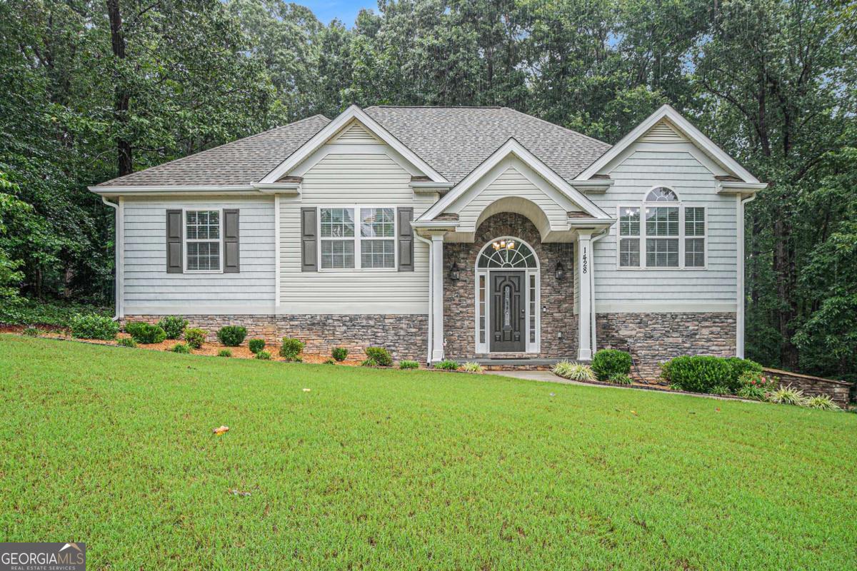 Welcome to 1428 White Oak Trace - A Private Retreat with Modern Upgrades in Loganville's Top-Rated School District Tucked away on a quiet cul-de-sac, this move-in-ready split-level home sits on nearly an acre of wooded privacy. From the moment you step onto the welcoming front porch, you'll appreciate the thoughtful upgrades and peaceful setting this home offers. Inside, you're greeted by an open concept layout with fresh neutral paint, brand-new flooring, and soaring vaulted ceilings in the fireside great room. The renovated kitchen features white cabinetry, granite countertops, tile backsplash, and stainless steel appliances, all illuminated by natural light and modern fixtures. A formal dining room and sunlit breakfast nook offer options for entertaining and everyday living. The owner's suite is a true retreat, featuring a tray ceiling, rich hardwood floors, and a beautifully updated bath that boasts dual vanities, a soaking tub, a separate shower, and stunning architectural details. Downstairs, the fully finished lower level features a versatile studio apartment/in-law suite, complete with a large bedroom, sitting area, flexible space, and full bathroom-ideal for multi-generational living or accommodating guests. Want more room? Inside the finished garage is a separate 10x10 area you can use for a workshop, exercise room, or hobby area. A step outside and you'll discover a true backyard oasis. The owner has transformed the outdoor space into a tranquil haven with professionally landscaped paths, a custom-built bridge over a creek, and a cleared picnic area tucked among the trees. The upper deck and covered patio offer multiple spaces to enjoy morning coffee, evening conversations, or weekend BBQs.Recent updates include a new roof (2018) and water heater (2021). All of this, located in the sought-after Loganville School District, close to shopping, dining, and parks.