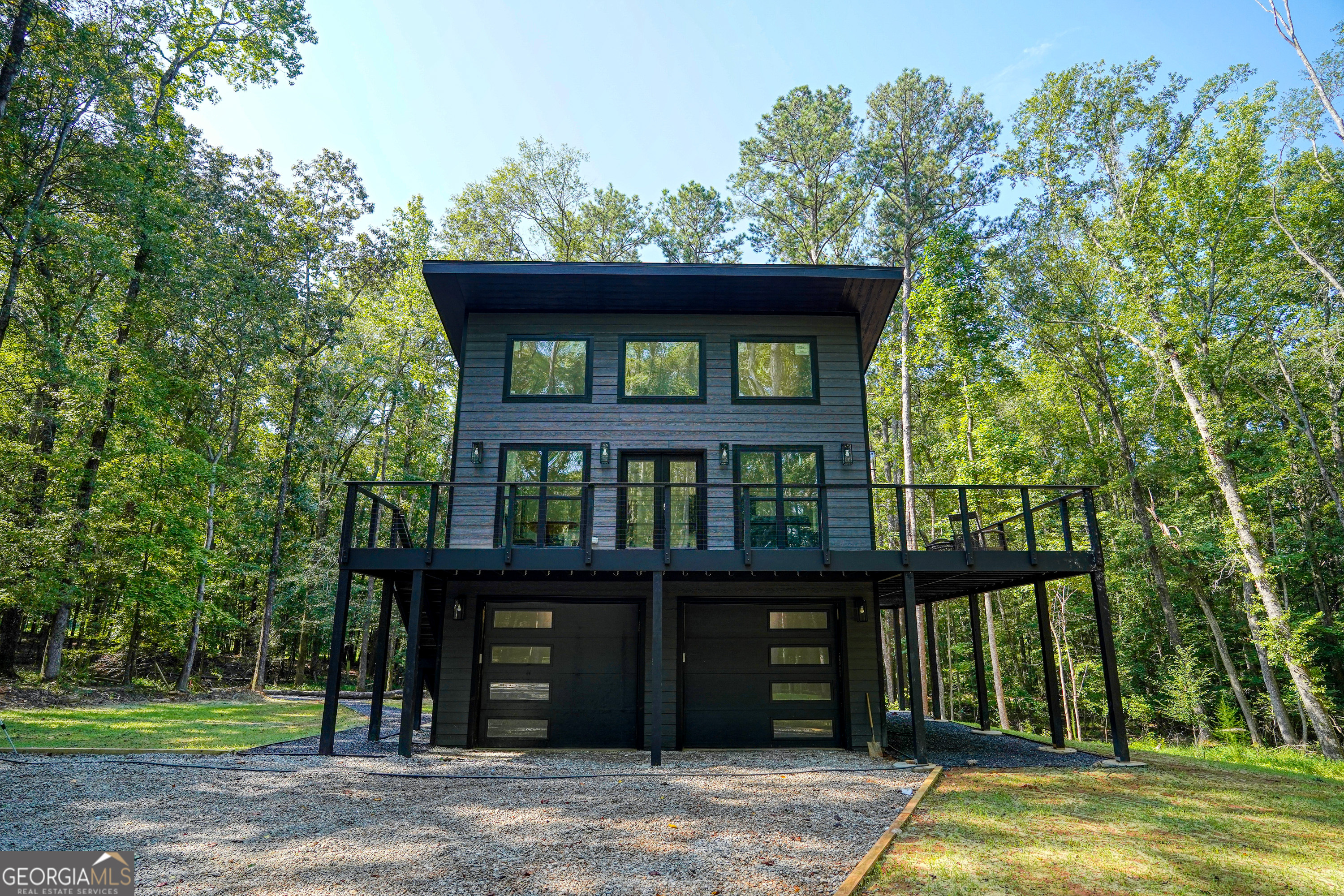 Discover a one-of-a-kind property where sleek modern design meets wooded serenity. Backing directly to a protected nature preserve, this brand-new home offers unmatched privacy, peaceful views, and a strong connection to the outdoors. The living space spans 700 square feet, complemented by an equally spacious 700-square-foot garage for unmatched versatility. Step into a light-filled open floor plan with high ceilings and a seamless flow between the kitchen, dining, and living spaces. Two sets of glass doors open to a wraparound deck with ample seating. The luxurious bathroom features a double vanity and a walk-in shower with a rainfall head and side body sprayers for a spa-like experience. A stackable laundry closet is conveniently located in the hall. The serene bedroom includes a mounted TV and direct deck access, creating a private sanctuary. A custom-built firepit on the property offers a cozy spot to gather under the stars. The spacious two-stall garage with soaring ceilings easily accommodates large trucks, boats, or production gear. A full bathroom on this level adds convenience. Designed for Extended Stays Whether you're bringing in executives, relocating employees, or housing cast and crew, this property delivers comfort, convenience, and privacy. High-speed internet, a fully equipped kitchen, in-unit laundry, and ample parking make it perfect for long-term corporate assignments or production housing. Prime Location Just off Highway 85 for quick commutes, you'll have easy access to Hartsfield-Jackson Atlanta International Airport and be only 10-15 minutes from Peachtree City and Trilith Studios. The location offers the best of both worlds: tranquil natural surroundings with fast access to major roads, dining, and area amenities.