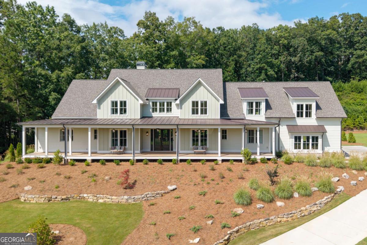 Ask about the Seller 5% buy down and preferred lender incentives. Elevated farmhouse - inspired living in Milton. This exquisite custom-built home in the Estate section of Crossroads, set on over an acre of manicured grounds, this home blends timeless elegance with modern luxury. A deep front porch frames sweeping treetop views, while 8-foot rear sliding doors open to a level backyard-ready for your dream pool and outdoor entertaining space. Inside, the open-concept design showcases a stunning chef's kitchen with an oversized island, microwave drawer, dual sinks, and custom shelving. The 48" Thermador 6-burner range with grill is framed by white cabinetry reaching 10-foot ceilings and a custom Subzero enclosure. A fully equipped prep kitchen features an additional sink, dishwasher, ice maker, beverage refrigerator, and walk-in pantry. The main-level primary suite offers French doors to the backyard, three custom closets, and a spa-like bath with generous built-ins. A guest suite with a private bath completes the main floor. Upstairs, discover three additional bedrooms with en-suite baths, a spacious bonus room perfect for the ultimate media space , and an open mixed use space ideal for a game room, fitness area, or study. Private rear stairs from the garage drop zone and secondary entry lead to an expansive unfinished space, ready to be transformed post closing to suit your vision. Custom window treatments add the finishing touch to this meticulously designed home. Enjoy walkable access to dining, shopping and services, plus the benefit of award-winning schools-all in one of Milton's most desirable locations.