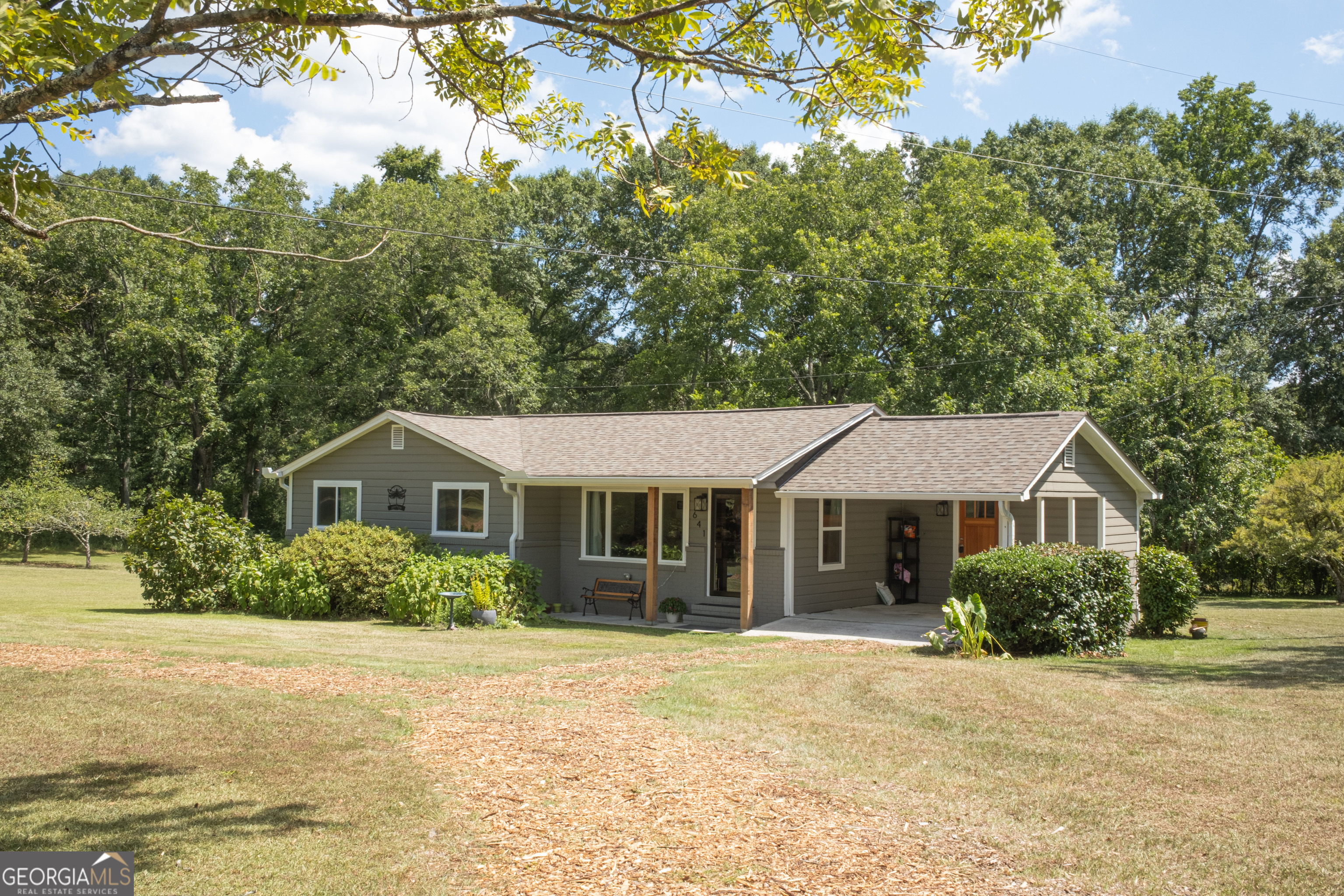 Welcome to Adytum-your private sanctuary just minutes from Downtown Senoia. This beautifully updated 3-bedroom, 2-bath home offers charm, comfort, and space to create. Inside, you'll find hardwood floors, an open-concept kitchen with abundant natural light, side laundry room, and a mudroom with extra storage. But the magic and beauty continues outside, the property boasts a massive 1,200 sq ft detached garage-air-conditioned and capable of housing up to six vehicles or your dream workshop/studio setup-plus an attached covered carport for additional parking. Enjoy fresh pears, apples, muscadines, from your own mature fruit trees, with nearly two acres, plenty of room to grow even more. Whether you're relaxing under the shade trees or working in your creative zone, this lovingly maintained home offers a rare blend of peaceful living and practical amenities-all just 40 minutes from Atlanta, 10 minutes from Downtown Senoia and a lovely local park just two minutes away.