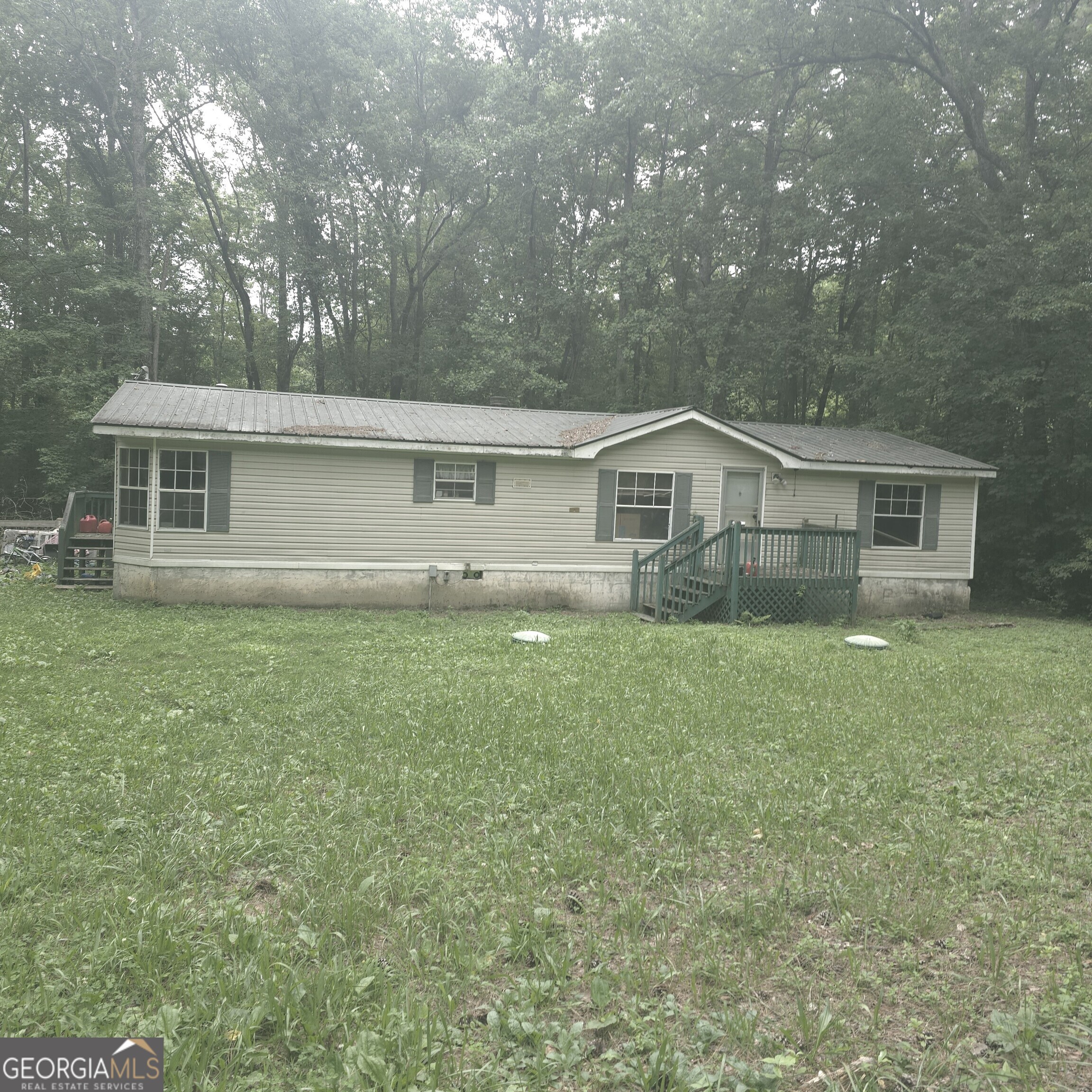 This 3-bedroom, 2-bathroom modular home is currently undergoing renovations, offering a fantastic opportunity to bring your vision to life. Set on a level lot, the property includes a fiberglass shower unit, new vanities in both bathrooms, and a commercial-grade toilet in the hall bath. The home comes with all remaining renovation materials, making it easy to pick up where the work left off. Enjoy added functionality with a dual septic system that operates like a mini processing plant an environmentally friendly solution along with a French drain surrounding the property. A peaceful creek runs along the back property line, and you'll cross a picturesque lake on your way into the neighborhood, adding to the charm. Inside, the pantry features a barn-style door and is ideally positioned between the dining area and the laundry room near the side entrance, which offers great potential for a future mudroom. The home was replumbed with PEX in 2020 for peace of mind. Located in a community with a mix of long-term ownership and rentals, this home is a blank canvas ready for your personal touches ideal for homeowners or investors alike!