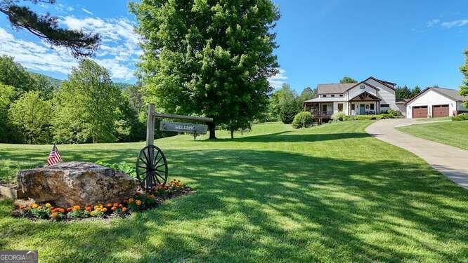 Rustic Farm Elegance Meets Modern Comfort in the Heart of Owltown! This immaculately maintained 4-bedroom, 3.5-bathroom craftsman farmhouse sits on 3.73 unrestricted acres in one of Blairsville's most sought-after areas. Blending rustic charm with modern sophistication, the home features high ceilings, hand-scraped hardwood floors, and quality craftsmanship throughout an open, airy floor plan ideal for everyday living and entertaining. The chef's kitchen is a showstopper with dual ovens, a gas range, stainless appliances, granite countertops, a custom tile backsplash, custom cabinetry, a large center island, and a dining area framed by abundant natural light. Offering flexibility and luxury, this home includes two owner's suites - the main-floor primary boasts a walk-in closet, garden tub, and a 6-foot tiled shower with dual shower heads, while the upstairs primary offers a walk-in closet, extra closet, double vanities, and another 6-foot dual-head tiled shower. A gorgeous loft overlooks the great room, perfect for a reading nook, office, or sitting area. The finished basement adds even more space with a flex room ideal for a home gym, media room, or guest accommodations. A wood-burning fireplace in the great room creates cozy warmth, while the second wood-burning fireplace on the covered back deck is perfect for entertaining or relaxing with breathtaking mountain views. Additional highlights include an oversized 27x27 attached garage, mudroom, and whole-house generator. Outside, enjoy covered porches, an outdoor fireplace, a butterfly garden, and a park-like setting surrounded by mountain scenery. Also included is a bonus 1.23-acre unrestricted property at 6151 Owltown Road, featuring a barn with bathroom, 3-car garage doors, pole barn, chicken coop, septic system, and water/power hookups - ideal for RV parking, a mini-farm, or a second home site. Combining rustic elegance and modern comfort, this property offers the ultimate mountain lifestyle!