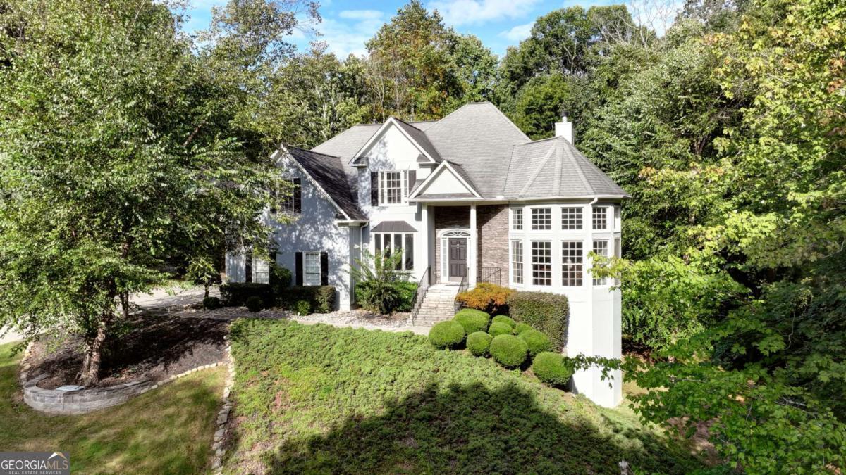 Welcome to this beautifully appointed 5-bedroom, 3.5-bath residence in Cumming's highly sought-after Chattahoochee River Club. Perfectly positioned on a private 1.55-acre lot with a picturesque creek, this home combines timeless architecture with modern updates and resort-style community amenities. Built with stone, hardcoat stucco, and HardiePlank, the exterior exudes durability and elegance. Inside, a soaring two-story foyer and newly installed hardwood floors set a grand first impression. The chef's kitchen boasts a large prep island with breakfast bar, granite countertops and backsplash, stainless steel appliances, double oven, gas cooktop, seamlessly connecting to the open-concept family room with a cozy fireplace. The remodeled baths add a touch of luxury, while the unfinished basement is already framed and includes a space configured and plumbed for a future wine cellar. Upstairs, the expansive primary suite offers room for a sitting area or home office, a large bath, and a huge walk-in closet. Generously sized secondary bedrooms include two with walk-in closets and one with a private ensuite. The main level also features a spacious dining room ideal for family gatherings or entertaining, plus a guest bedroom for those overnight stays. A four-season sunroom and deck overlook the private wooded backyard, providing year-round enjoyment. As part of the Chattahoochee River Club, residents enjoy premier amenities: swim and tennis facilities, clubhouse, pickleball and basketball courts, baseball and soccer fields, playground, and miles of scenic walking trails along the Chattahoochee. With national award-winning schools-Haw Creek Elementary and South Forsyth High-nearby, plus a short drive to Cumming's new City Center, this home truly has it all.