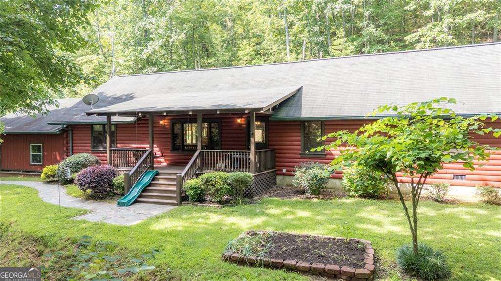Welcome to your dream retreat! Nestled at the base of John's Mountain in the picturesque Chattahoochee-Oconee National Forest, this custom-built log cabin is a serene sanctuary offering unrivaled peace and tranquility. The cabin features pine floors throughout, providing a warm, rustic charm. The heart of this home is an open floor plan that seamlessly connects the living room, dining area, and kitchen, creating a spacious environment perfect for entertaining. With three bedrooms and two full baths, this home offers ample space for family and guests. Discover the expansive primary suite, a haven of privacy and comfort. This versatile space provides ample room for a cozy sitting area or an office setup, allowing for ultimate relaxation and functionality. Additional amenities include a separate storage building and a versatile structure that can function as a playhouse or garden shed. The property spans five acres, richly adorned with hardwood trees and a gentle stream, harmonizing nature's beauty with your everyday life. Embrace the tranquility and make this unique log cabin your home today!