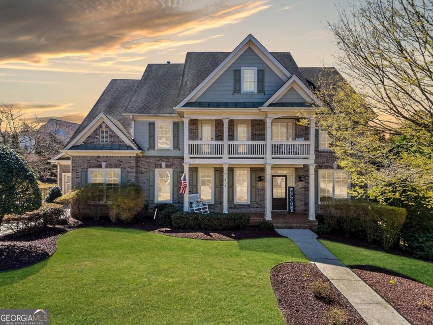 Standing gracefully in the heart of River Green, this stately home boasts a commanding presence with its three-sides brick exterior and double-stacked porches, offering both architectural beauty and functional outdoor living spaces. The welcoming front entrance opens to a soaring two-story foyer, where natural light cascades from above, accentuating the grand staircase and warm hardwood floors that flow throughout the main level. To the right, a private office or formal living room offers a quiet space for work or relaxation. Beyond, the oversized dining room captivates with its coffered ceiling, setting an elegant stage for gatherings. A butler's pantry seamlessly connects the space to the gourmet kitchen - quipped with granite countertops, an expansive center island, a gas cooktop, double ovens, and an abundance of cabinetry. A walk-in pantry ensures plenty of storage, while the breakfast area's bump-out bay window fills the space with sunlight. Anchoring the main floor is the keeping room, where a stone-surround fireplace and built-in bookshelves create a cozy retreat just off the kitchen. In the adjacent two-story great room, a wall of windows stretches from floor to ceiling, offering breathtaking views and an infusion of natural light. A gas fireplace with built-in cabinetry adds both warmth and sophistication. Completing the main level, a private bedroom with a full bath provides comfort and convenience for guests. Upstairs, the oversized primary suite is a retreat of its own, featuring a sitting area and an en suite bath with double vanities, a walk-in shower, a whirlpool tub, and an immense California Closet system - designed with custom shelving and enough space to accommodate an office. A secondary bedroom enjoys a private full bath and direct access to the upper porch, offering a peaceful outdoor escape. Two additional bedrooms, connected by a Jack-and-Jill bath, provide ample space for family or guests. A huge laundry room with built-in storage and a utility sink adds functionality to the upper level. The walkout basement expands the home's living space with a bonus room, an additional bedroom and full bath, and a wet bar equipped with a sink, wine fridge, and ice maker - perfect for entertaining. Ample storage ensures every item has its place. Outside, the level, fenced backyard provides the perfect setting for outdoor enjoyment, whether for quiet afternoons or lively gatherings. A three-car garage, consisting of a two-car bay plus a separate third bay, offers flexibility for vehicles, storage, or workspace. From its stunning architectural details to its thoughtfully designed interior, this home is a testament to both craftsmanship and comfort - a true gem in the heart of River Green's Reynolds Park.