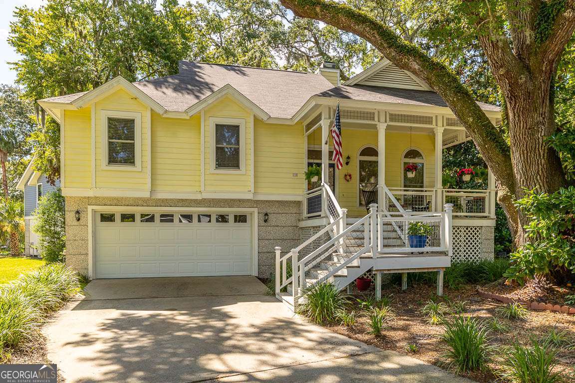 Welcome to this island cottage, just a stone's throw from the beach-only a mile away! Tucked away at the end of a peaceful cul-de-sac beneath the sweeping arms of grand old live oaks, this lovingly cared for coastal home is full of charm. From the moment you step inside, you'll feel the easy, coastal vibe, featuring a vaulted great room with a cozy wood-burning fireplace, a cheerful dining area, and a spacious kitchen outfitted with breakfast area. Enjoy your morning coffee or evening cocktail in the sunroom just off the kitchen-or kick back on the covered front porch overlooking a lagoon with fountain. Inside, this home glows with personality, Parquet flooring and a fun multi-level layout. The spacious primary suite is tucked away for a little peace and quiet, complete with walk-in closet, and an updated bathroom with huge shower. Two more light-filled bedrooms and a shared hall bath make guests or family feel right at home. Downstairs, the garage level offers even more space to relax and enjoy, whether you turn it into a game room, extra bedroom, or the ultimate rec space. With plenty of storage, a two-car garage and all the charm you could ask for, this home is ideal as a full-time retreat or a part-time getaway. Come on in and stay awhile. The island life is calling!