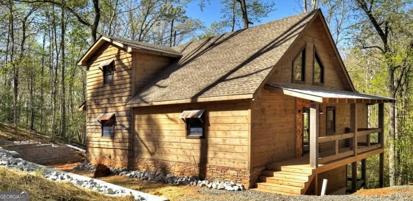 Gorgeous cabin located in the gated Coosawattee River Resort just moments away from the Coosawattee River! Primary suite is on the main floor and has a massive bedroom and bathroom with a custom shower, custom cabinetry, a stunning copper bathtub, private water closet, and laundry room located conveniently in the master closet. Upstairs bedroom suite also has an abundant amount of space with its own private porch. The kitchen has dark, stainless GE appliances, beautiful custom cabinetry, wrap around stone backsplash, tons of storage space, open shelving made from reclaimed wood, and an oversized island with a concrete top you must see for yourself! The living room boasts a stunning staircase and a floor to ceiling, gorgeous stone fireplace. Both the basement and the main floor have amazing porches that run the full length of the home, perfect for enjoying all the wildlife that surrounds you in this serene area. The main floor porch also includes a gas fireplace for relaxing on those chilly fall nights. The basement is partially finished, has a hookup for a washer/dryer, and is plumbed for a bathroom as well. It is a fresh canvas that can be anything you need it to be! This is the perfect place for your primary residence, your weekend getaway, or a short-term rental! This home has the perfect blend of modern convenience and the charm of the mountains. Located just minutes from shopping, dining, wineries, and orchards, yet it feels tucked away in the peace and serenity of nature. The Coosawattee River Resort offers two outdoor pools and one indoor, heated pool which is open year-round. The vast array of amenities also includes an arcade, a fitness center, an 18-hole putt putt golf course, tennis and pickleball courts, parks, and river access for tubing, swimming, and kayaking! SO MANY EXTRA DETAILS YOU MUST SEE FOR YOURSELF! Make an appointment today!