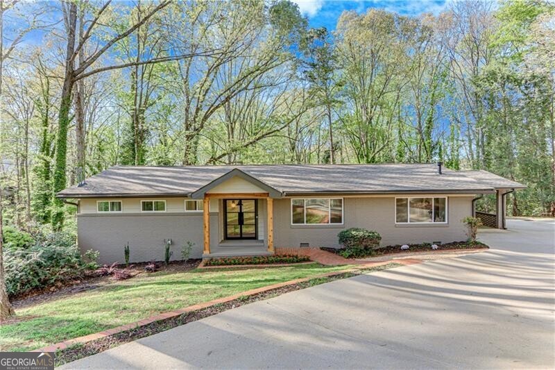 Stunning mid-century in the heart of Gainesville, located on a quiet street in a Lake Lanier neighborhood with seasonal lake views. Enjoy privacy with well-spaced homes and a serene backyard setting. This stunning home features wrought iron exterior doors, a fireplace flanked with built-ins, and a beautifully reimagined island kitchen with custom white oak cabinetry, open oak shelving and quartz counters, with stainless KitchenAid appliances. The main-level owner's suite offers a luxurious double-headed shower and a custom walk-in closet. The sunroom across the back, with its own exterior entry, is ideal for a home office. The terrace level includes not only living/dining space with a bar, sink and Kitchen-Aid fridge, but also a bedroom suite, a bonus room for hobbies or storage, and a second laundry room. Nearly everything is new: windows, plumbing, electrical, roof-and washer/dryer on main level. A rare blend of timeless style, functionality and location. No HOA. Owners are agents.