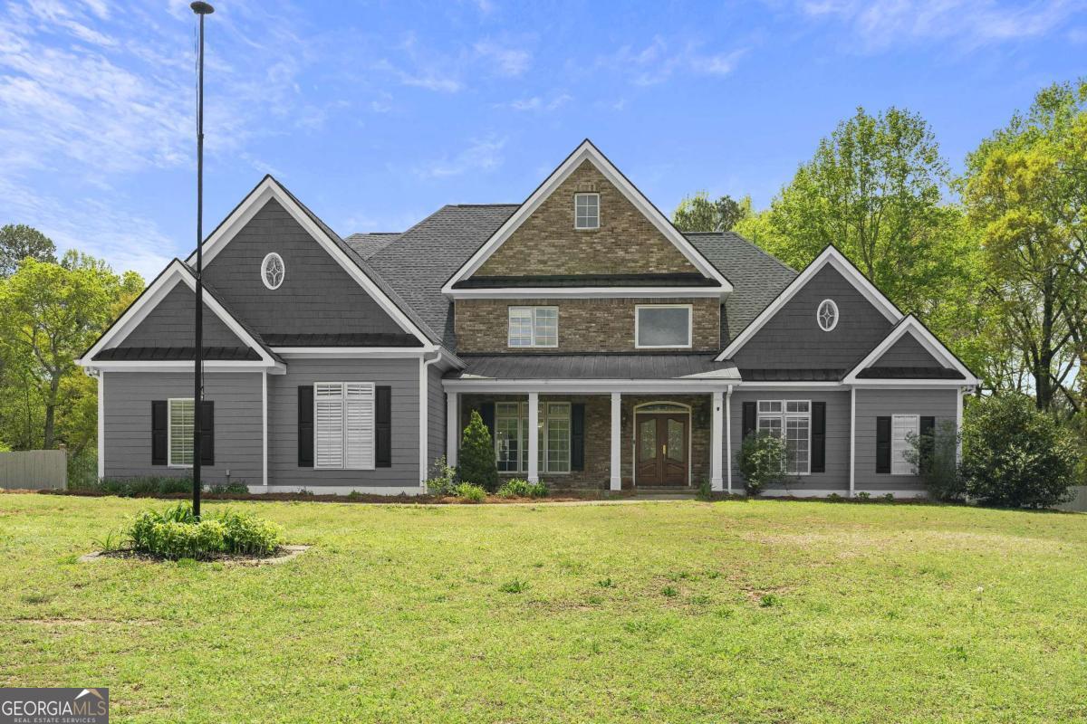 Welcome to this truly exceptional custom built estate nestled on a level two acre lot in sought after East Cobb with NO HOA! From the moment you arrive, the charm begins with a welcoming covered front porch and continues inside, where a grand two story foyer sets the tone for the elegance within. The home boasts nearly 6,000 square feet of beautifully crafted living space, including a soaring two-story great room filled with natural light from dramatic floor-to-ceiling Pella casement windows. Rich cherry hardwood floors, intricate millwork, and thoughtful details like a central vacuum system with a dustpan feature make this home as functional as it is stunning. Designed for both daily living and grand entertaining, the main level features an oversized primary suite with dual walk-in closets and direct access to a spacious tiled screened-in deck overlooking the private, fenced backyard. The gourmet kitchen is outfitted with high-end Kitchen Aid stainless steel appliances and flows seamlessly into a cozy breakfast area and formal dining room. Upstairs, you'll find three generously sized bedrooms, each with en suite baths, including a secondary master suite with an expansive walk-in closet illuminated by natural light. The full daylight terrace level offers incredible versatility with ten foot ceilings, a second full kitchen, a movie room, game room, and additional living spaces perfect for generational living or entertaining. A covered patio just off the basement provides even more space to enjoy the serene backyard, ideal for a future pool or tennis court! Need storage or workspace? In addition to a three-car garage, there is a fourth rear-entry garage deep enough to accommodate two vehicles. This is more than just a home, it is a lifestyle