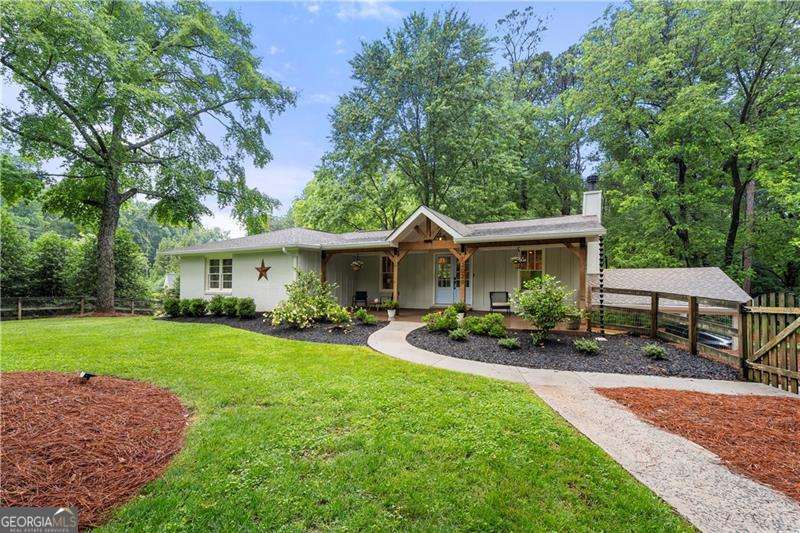 Tucked in a storybook corner of Marietta, this picture-perfect, cottage-style ranch isn't just a home-it's a vibe. Set on a spacious, level lot with a fully fenced front yard, this home invites both curb appeal and function. It's the kind of setting that feels like a quiet retreat, yet it's just minutes from I-75, historic Marietta Square, and a straight shot to Braves games and the heart of Atlanta. Inside, character and craftsmanship greet you immediately. Vaulted ceilings with exposed beams, gleaming hardwoods, and a show-stopping wormwood maple island bring warmth and personality to the open-concept living space. Shiplap details and a cozy fireplace add just the right amount of charm, while the reclaimed utility sink in the hall bath offers a nod to the home's thoughtful design choices. Upstairs, you'll find three spacious bedrooms and two full baths, while the finished basement offers so much more-two additional bedrooms, full bath, and a bonus space ideal for hobbies, play, or working from home. Plus, with generous closets and a large laundry room, storage and function are fully covered. This home offers the best of both worlds: a thoughtfully updated interior, a dream-worthy yard, and a location that puts you close to everything.