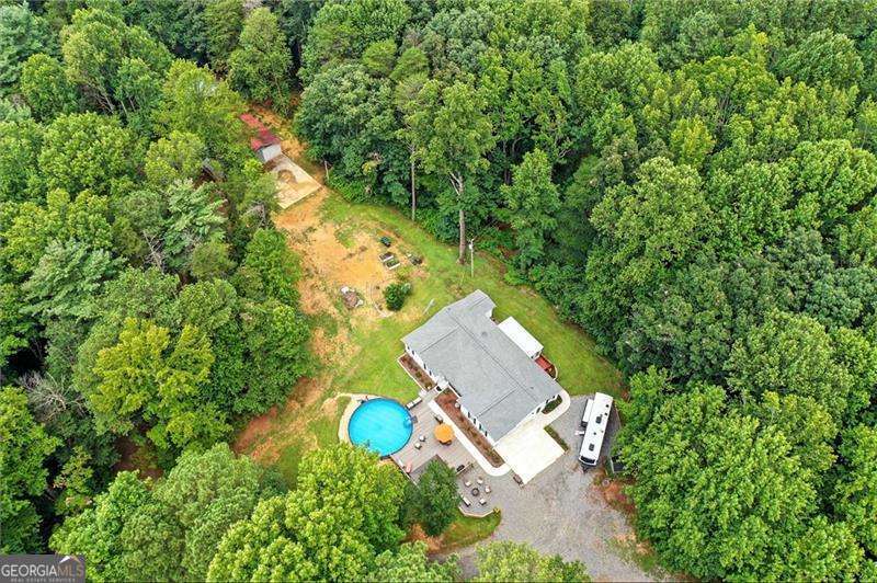 Country living with room to grow on acres! This well-maintained 3-bedroom, 2-bath ranch home is situated on 5.9 acres of peaceful land-perfect for those looking for space and privacy. This charming home offers potential in a beautiful rural setting. Inside, the home features a functional layout with a cozy living area, spacious kitchen, and comfortable bedrooms. The master bedroom is on the main level and includes an en-suite bath. Both of the secondary bedrooms are generously sized and have walk-in closets. The living room has a fireplace and a bay window. The country kitchen is well equipped and has a kitchen peninsula with seating for 4. The eat-in kitchen nook has room for all your guests. The enclosed back porch is perfect for morning coffee or for entertaining. There is a large pantry/ storage room off the kitchen perfect to keep all of your things. Step outside and enjoy summer days at the above-ground pool and relax and entertain on the large Trex deck -durable, low-maintenance, and built to last! Entertain your guests at the fire pit under the bright stars found only in the country away from the bright city lights. Whether you're hosting friends, enjoying a quiet morning coffee or end-of-day beverages, the outdoor space is sure to impress. Included on this property is a separate barndominium in process with a large parking pad/slab that has a newly installed septic system. This project was started by the seller and it offers a fantastic opportunity to finish this project your way. Cabinets, new kitchen appliances and a water heater will be included. Large concrete pad next to this structure is in place for a parking area or when you build the new garage. Whether you're dreaming of a guesthouse, workshop or studio, the groundwork is already in place. With almost 6 acres to roam, there's plenty of room for animals, gardening, or simply enjoying nature. No HOA. Bring your vision and enjoy all the benefits of country life just a short drive from Ellijay. So many upgrades to list here. This property has a new Generac back up power system. There are two wells on the property and one was just completed in 2024. Crawl space under the 3 bedroom home has a recently installed vaper barrier and is humidity controlled. Don't miss the chance to make this property your own-schedule your private tour today!