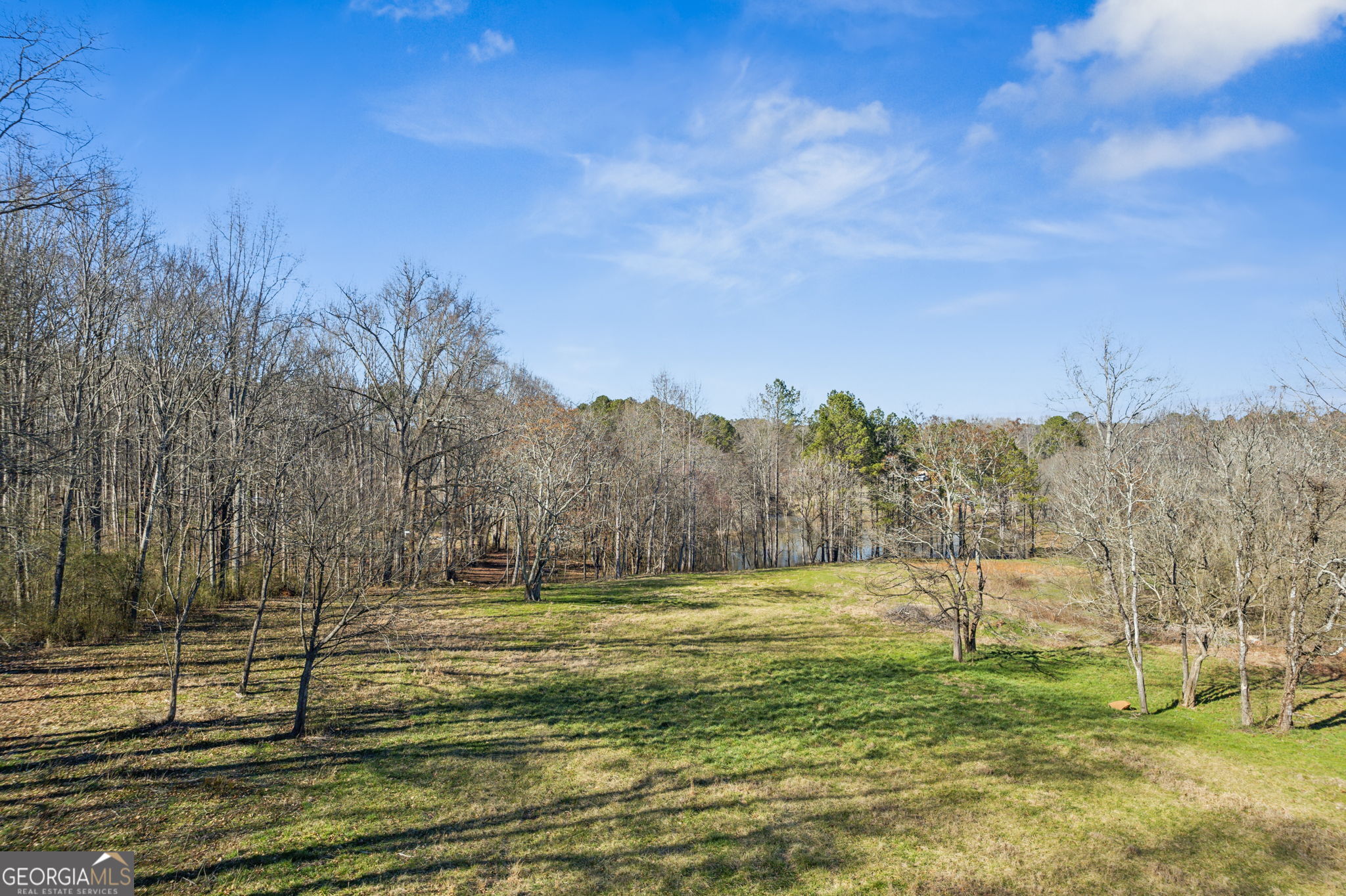 This exceptional 27-acre parcel on Hickory Flat Hwy/Hwy 140 in southeastern Cherokee County offers an ideal mix of pasture and woodlands, level to gently rolling topography, a 3-acre pond, and frontage on Mill Creek. The back portion of the property provides exceptional privacy, bordering county-owned Sequoyah Park. With all utilities available, including sewer, and located just one mile from the Hickory Flat commercial hub-home to Publix, Chick-fil-A, Tractor Supply Co., and a brand-new Starbucks-this is one of the last large, undeveloped tracts along Hwy 140. An additional 2.5 +/- acres may be available, and as an added bonus, the property includes a 3-bedroom, 2-bathroom brick ranch. Don't miss this rare investment or estate opportunity!