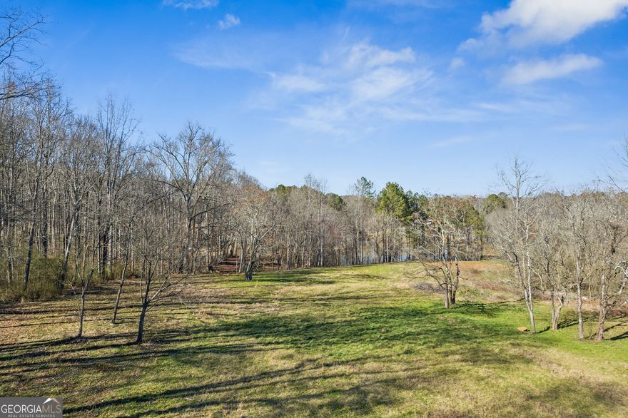 This exceptional 27-acre parcel on Hickory Flat Hwy/Hwy 140 in southeastern Cherokee County offers an ideal mix of pasture and woodlands, level to gently rolling topography, a 3-acre pond, and frontage on Mill Creek. The back portion of the property provides exceptional privacy, bordering county-owned Sequoyah Park. With all utilities available, including sewer, and located just one mile from the Hickory Flat commercial hub-home to Publix, Chick-fil-A, Tractor Supply Co., and a brand-new Starbucks-this is one of the last large, undeveloped tracts along Hwy 140. An additional 2.5 +/- acres may be available, and as an added bonus, the property includes a 3-bedroom, 2-bathroom brick ranch. Don't miss this rare investment or estate opportunity!