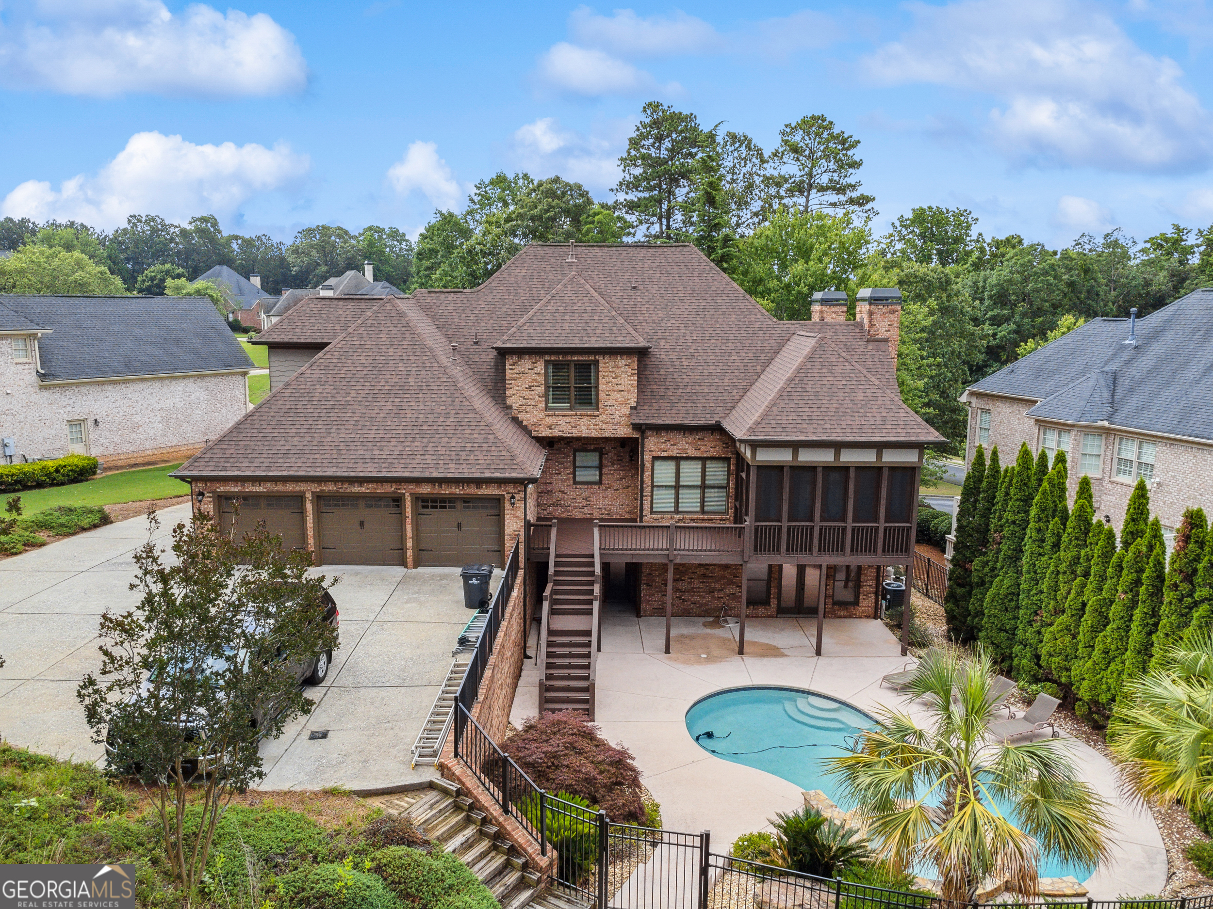 Welcome to The Enclave - This stunning custom residence is the personal masterpiece of a professional cabinet and trim maker, gated community just minutes from top-rated schools, fine dining, and upscale shopping-with quick, convenient access to I-85. Crafted by a master cabinet and trim artisan, this home is a showcase of timeless luxury and detail. From the stately two-story foyer to the hand-finished woodwork, every inch speaks to quality and care. Step into the formal dining room, where layered crown molding, custom wall textures, and a stunning bay window create an atmosphere of classic elegance-perfect for hosting memorable dinners beneath a sparkling chandelier. Just off the foyer, the piano room or private study is a showstopper with rich, floor-to-ceiling cherry wood paneling, a coffered ceiling, and a fireplace that adds warmth and sophistication-ideal for music, reading, or executive work-from-home needs. The heart of the home is the fireside great room, where a dramatic vaulted ceiling with exposed wood detail rises above built-in bookshelves and a floor-to-ceiling stacked stone fireplace. This inviting space blends comfort with grandeur and is perfect for cozy nights or lively gatherings. The chef's kitchen is designed to impress, featuring custom cabinetry, an oversized island, a walk-in pantry, and seamless flow into the breakfast and keeping rooms, which open to the covered outdoor living space-ideal for morning coffee or evening cocktails. The main-level primary suite is a luxurious retreat with a sitting area, spa-like bath including a jetted tub and separate shower, and dual walk-in closets designed for organization and beauty. Upstairs offers three oversized bedrooms, each able to accommodate king-sized furniture, with en-suite or jack-and-jill baths offering comfort and privacy. The finished terrace level includes a full kitchen bar, a large office or media room, a recreation and gym space, a pool table room, a full bath with steam shower, additional bedroom and direct walk-out access to the backyard oasis. Outside, you'll find a resort-style paradise with a heated saltwater pool, jetted spa, palm trees, and a custom stone patio designed for outdoor entertaining. A fenced section offers privacy and security-perfect for pets and children. Additional features include two gas fireplaces, gleaming hardwood floors on the main level, main-level laundry, and a discreetly positioned three-car garage. This is more than a home-it's a lifestyle. Schedule your private tour today and experience the unmatched charm and quality of this one-of-a-kind residence in The Enclave.
