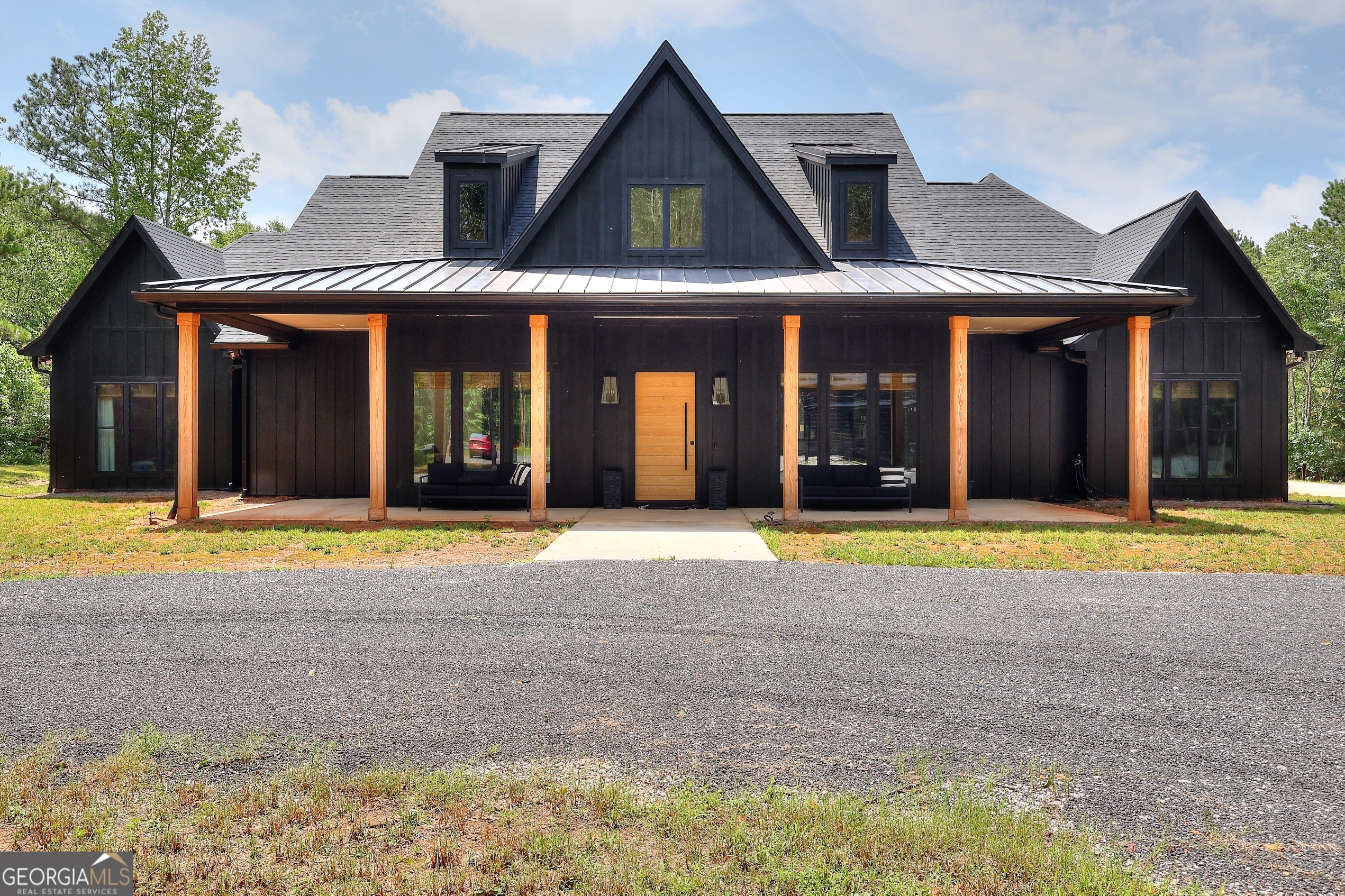 Where Luxury Meets Land: A Private oasis just minutes from it all tucked away on a quiet street this 11.21-acre estate offers the rare blend of total privacy and unmatched convenience all while being centrally located to downtown Monroe, Loganville, Barrow Crossing, and the new YMCA. This custom-built home was designed for those who crave space, style, and smart living. Offering over 3,800 sq ft this home is packed with thoughtful upgrades and warm, modern finishes. From the moment you step through the solid white oak pivot front door into the 20-foot, two-story foyer, you are met with an open-concept design while showcasing your lush backyard through a 16 x 8 ft sliding glass door. At the heart of the home, a 10-foot quartz island anchors the kitchen, outfitted with a gas range, champagne bronze accents, and a moody walk-in pantry featuring custom bookcase-style shelving, a dry bar, and a built-in mini fridge. The living room's venetian plaster gas fireplace adds a cozy focal point, while the adjacent outdoor wood-burning fireplace (with gas starter) creates the perfect setting for cool evenings under the stars. The primary suite is a retreat of its own, with a spa-style bathroom, dual vanities, and direct access to the laundry room that is complete with quartz counters and ample storage. Two additional bedrooms share a jack-and-jill bath, while a fourth has its own ensuite. Upstairs, a versatile bonus room features a full bath, closet, mini-split, and a wall of custom cabinetry making it perfect for an oversized fifth bedroom, a home office, media room, or flex space. Modern living is easy here: enjoy instant, endless hot water with a recirculating tankless system, climate control through Nest thermostats and dual HVAC units, spray foam insulation throughout, and ethernet hardwiring to all TV locations for fast, seamless streaming. The climate controlled 3-car garage and oversized attic storage with stair access add even more functionality. Outside, you'll find a grand, vaulted ceiling perfectly highlighting the mature oak trees. A custom outdoor kitchen with a 7-foot island, two mini fridges, a built-in Blackstone, and a Bullseye pellet grill that is ready to host everything from Georgia game day BBQs to quiet summer nights with friends or family. Also included with this showstopping property is a 2,100 sq ft metal shop with spray foam insulation, two 9-foot fans, a lean-to for equipment, and endless potential for when you need extra space for work, hobbies, or just weekend toys - this is it! This private property offers a custom gated drive with keypad, cellular video, and audio service. Ensuring easy access in all seasons, the asphalt milling driveway completes this picturesque property. If you're looking for a home that feels like a retreat but lives like a modern masterpiece, this is the one.