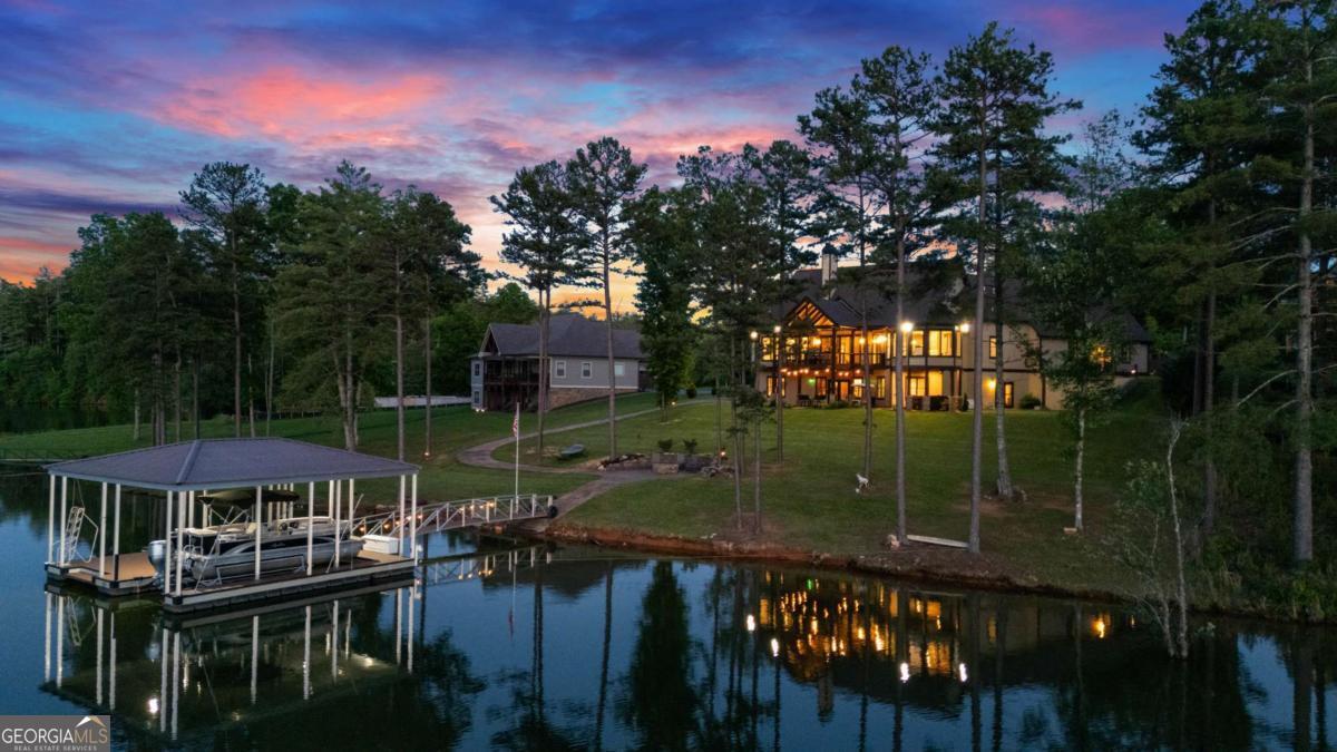 Set against the breathtaking backdrop of Lake Nottely and the Blue Ridge Mountains, this masterfully crafted 4-bedroom, 4-bathroom home is a standout residence within the prestigious gated community of The Grove at Highland Park in Blairsville, GA. Designed to capture sweeping lake and mountain views, the main level features an open layout with vaulted tongue-and-groove ceilings, exposed beams, a dramatic stacked-stone fireplace, and a wall of windows that flood the space with natural light. The gourmet kitchen boasts granite countertops, high-end stainless steel appliances, a gas cooktop, walk-in pantry, and a stylish dining area ideal for entertaining. A private office with a full bath offers flexible use as a home office or additional bedroom suite. The owner's suite is a serene retreat with lake views and a spa-inspired bathroom featuring a garden tub, dual vanities, and a glass-and-tile walk-in shower. Step outside to a covered deck overlooking the water, perfect for relaxing and enjoying the scenery. The terrace level offers a fully independent living space with a second kitchen, laundry room, three bedrooms, two bathrooms, a cozy living area with fireplace, and a spacious game room. Glass doors open to a covered patio and private hot tub with tranquil lake views. Outdoor living is enhanced by professionally landscaped grounds, a stone fire pit by the shore, and a private golf cart path leading to a 2-slip covered dock with boat lifts and swim platform. Residents enjoy luxury amenities including a clubhouse with infinity pool, fitness center, theater, pub/game room, grilling stations, boat parking, and expansive lakeview decks. Combining elegant design, thoughtful features, and stunning natural surroundings, this exceptional home offers an unparalleled lifestyle in North Georgia.