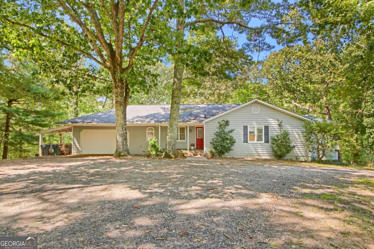 Welcome to your own private retreat on 2 acres with NO HOA! This spacious 4-bedroom, 4-bath ranch with a full finished basement offers comfort, versatility, and a beautiful natural setting. Inside, you'll find lots of space with living areas full of natural light. The updated kitchen features a 2-year-old GE French door refrigerator along with a KitchenAid stove, microwave, and dishwasher-combining modern convenience with timeless style. Just off the kitchen and large dining area, an inviting family room with vaulted ceiling and a wood-burning fireplace creates the perfect spot for gathering. The generous owner's suite with skylighted oversized bath opens into a stunning sunroom with more skylights. Two oversized secondary bedrooms and a full bath complete the main level. The fully finished basement expands your living space with two large rooms (ideal as extra bedroom, office, or exercise spaces), plus a full bath, a spacious open living area with wood-burning stove, a large laundry room, and tons of storage, including unfinished areas and under the stairs. This level's separate plumbing and private exterior exit provide the possibility of income potential, if desired. Outdoor living shines here with an expansive back deck overlooking wooded views, a large backyard with storage shed, wooded acreage to explore, and a welcoming front porch offering lovely pastoral views of the neighboring horse farm. A two-car garage (with attic space for extra storage above), plus an extra carport and large circular driveway provide plenty of parking and make coming and going easy! A newly installed Starlink satellite system with a 150-foot buried cable ensures simple, reliable internet connectivity. This property delivers the perfect balance of privacy and convenience-just minutes from Hwy 400, the outlet malls, and all that North Georgia has to offer.