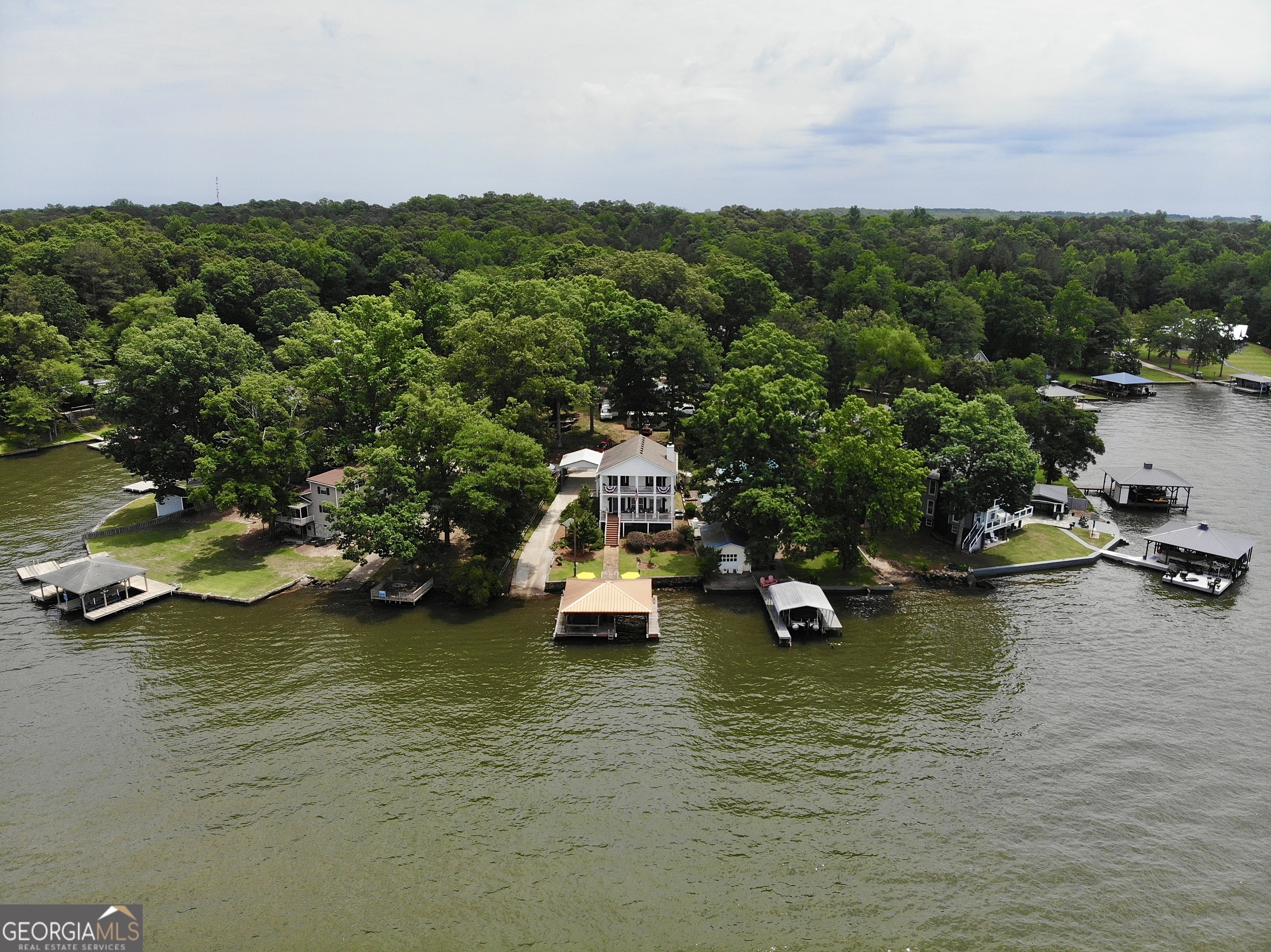 Beautiful lake views from all living spaces! Double doors open up to the walk out deck off of all bedrooms and family room. Updated with new countertops, center island and big kitchen that overlooks the large family room and the lake. New wood floors throughout. Large bedrooms, both with ensuites. Primary bedroom has large walk in closet and double vanity. Beautifully updated walk-in showers with new tile and glass doors. Wonderful, covered dock with one boat slip great for relaxation or entertaining. Private boat ramp. Outbuilding for ample storage. Deeded lot. This is a one of a kind beauty!