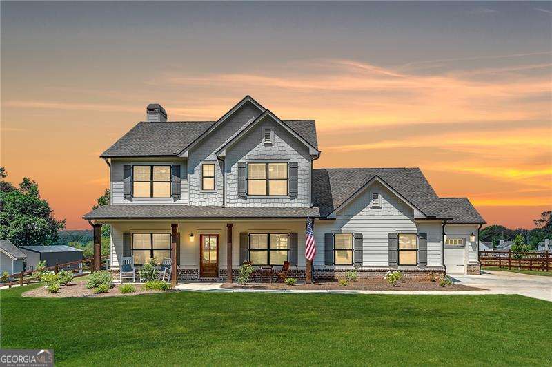 Welcome home to this nearly new, custom-built modern farmhouse nestled on 2 private acres, offering timeless elegance, high-end finishes, and stunning sunset views. With a welcoming rocking chair front porch and a spacious 3-car garage, this home blends country charm with refined design. Inside, you'll find a light-filled, open floor plan featuring wide-plank hardwood floors, rich trim work, and an elegant formal dining room. The heart of the home is the designer kitchen-complete with crisp white and slate cabinetry, a large quartz island, gas cooktop, pot filler, and soft gold fixtures-opening seamlessly into the fireside family room, perfect for gathering and entertaining. This thoughtfully designed home features 4 spacious bedrooms and 3 full bathrooms, including a main-level guest suite. The upstairs owner's suite offers a tray ceiling, walk-in closet, and a luxurious spa-inspired bath with dual vanities, soaking tub, and glass-enclosed shower. A separate office on the main floor provides an ideal space for working from home. Step out back to your own peaceful retreat-an expansive covered back porch with a built-in TV wall and grilling area, overlooking a large fenced yard where you can enjoy some of the most beautiful sunsets Georgia has to offer. Tucked away for total privacy yet only minutes from local conveniences and the breathtaking shores of Lake Varner, this exceptional property is a rare find for those seeking quality craftsmanship, space, and serenity.