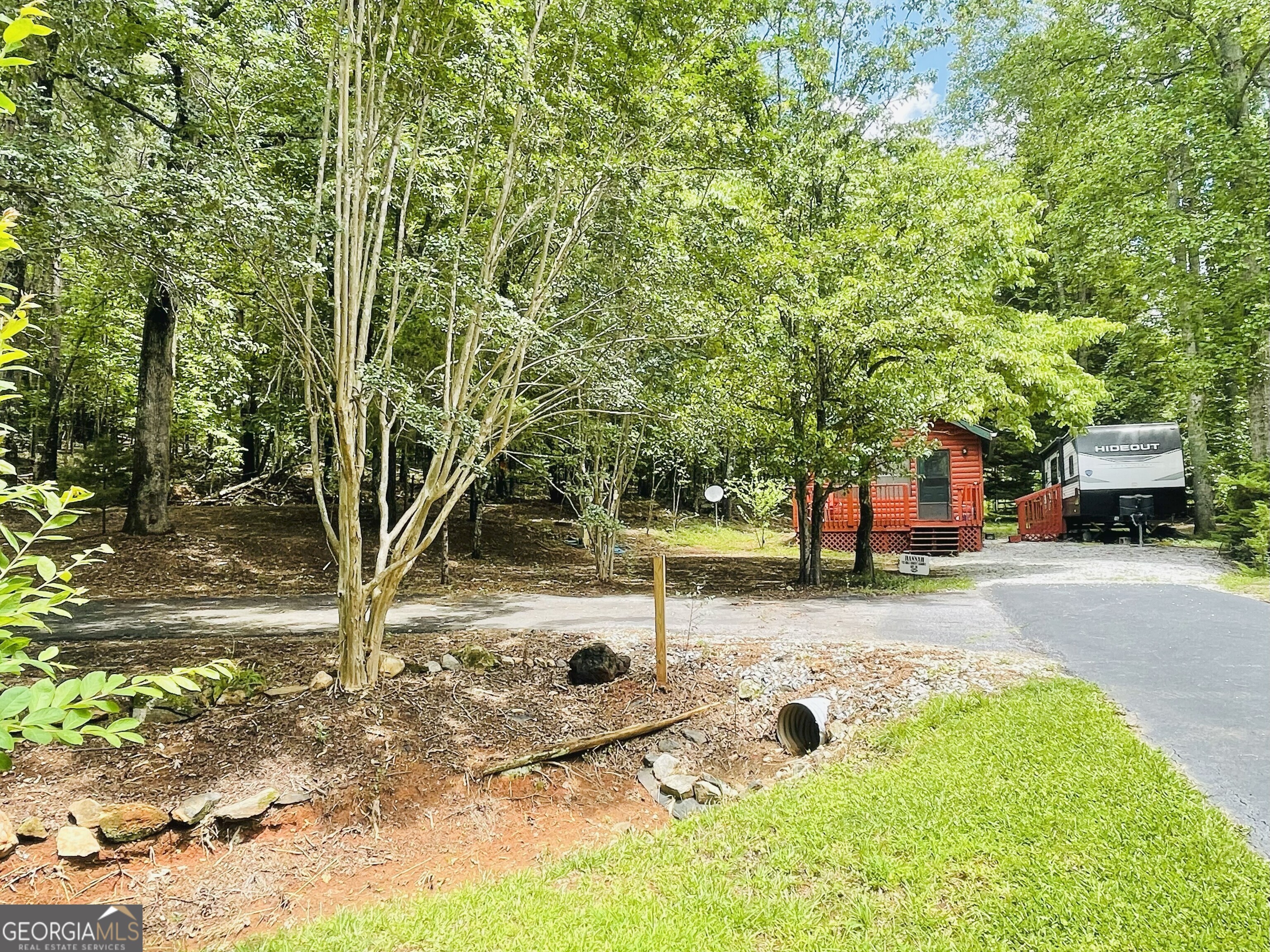Escape to the beauty of the North Georgia Mountains in the sought-after Paradise Valley Campground, conveniently located near Cleveland, Helen, and Dahlonega. This unique and spacious 1 +/- ac corner lot with cabin features two full hookups and a camper making it perfect for hosting guests, setting up multiple RVs, or expanding your vacation space. Included in the sale is a lightly used and a 2021 Hideout Camper that has only been slept in a handful of times, offering immediate use and value. The cabin is currently under construction with potential for a loft-providing flexibility to customize your mountain retreat just the way you envision. Surrounded by nature and outdoor adventure, this location puts you close to everything North Georgia has to offer. Explore local wineries, enjoy day trips to Unicoi and Vogel State Parks, or hike parts of the legendary Appalachian Trail. The area also offers whitewater rafting, kayaking, scenic drives, and charming mountain towns filled with restaurants, breweries, and artisan shops. Paradise Valley Campground offers a well-maintained and welcoming community with amenities like a swimming pool, clubhouse/pavilion, and regularly scheduled activities for those who enjoy a sense of community and social interaction. A peaceful trout stream runs through the property, enhancing the serene environment. **Please note, this is a seasonal-use community and does not allow full-time living.** This property is ideal for weekend getaways, part-time stays, or vacation rental potential. Making this the perfect opportunity to own a piece of the North Georgia mountain lifestyle.