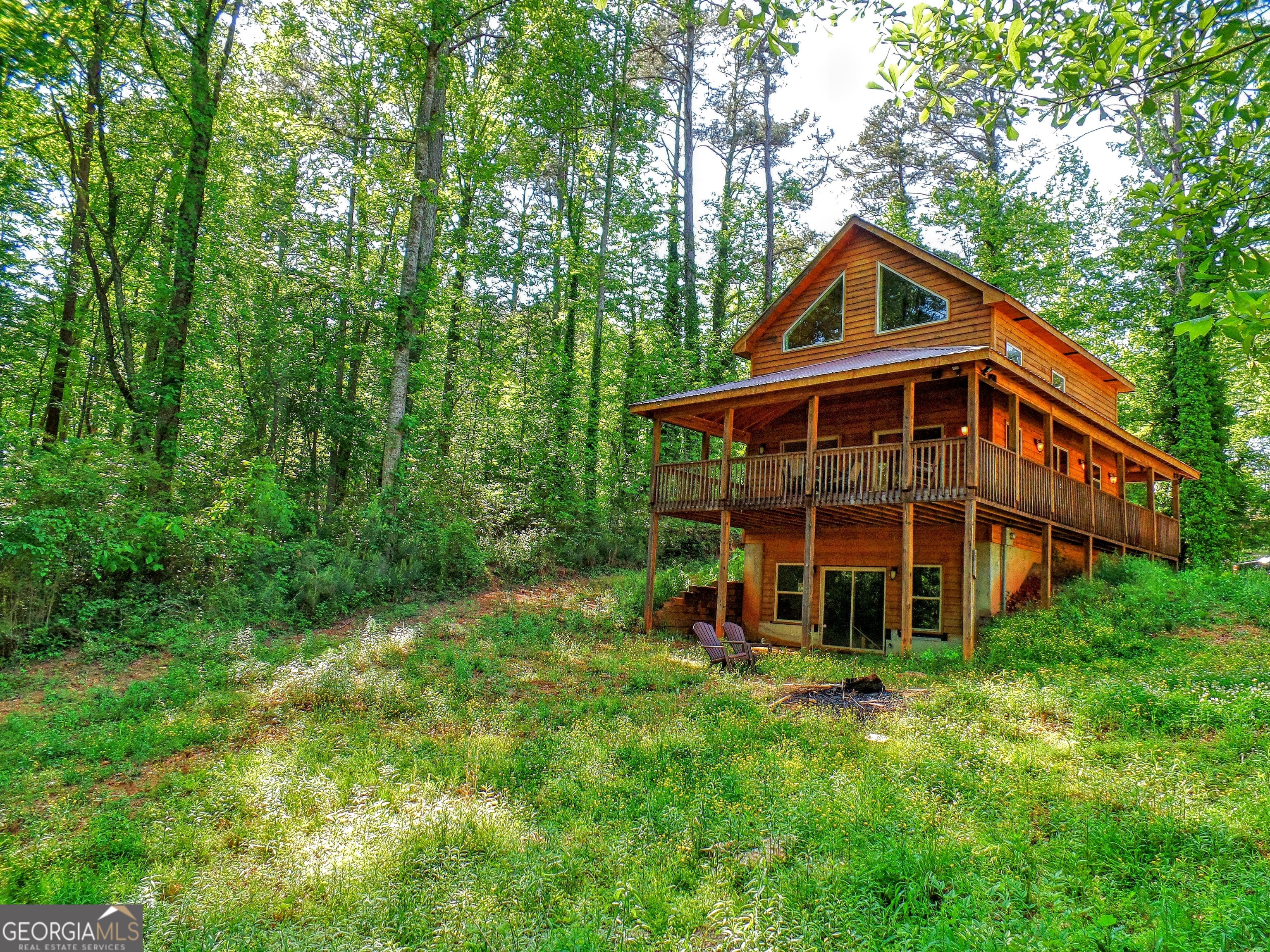 Lake Lanier living in this resort style cabin! Easy, easy walk to the single slip Trex party dock in deep water available for tie-up only storage. Gleaming all wood cabin with soaring ceilings and open concept floor plan. Windows everywhere, high and low, provide wonderful natural light and make the most of the wooded lot views. Spacious loft bedroom looks out into the treetops. Enjoy a morning coffee, an afternoon nap or an evening refreshment on the covered back deck with wrap around porch. Full unfinished basement yields plenty of storage. Private, and yet .... just minutes from shopping and life's necessities! Call for a private showing.