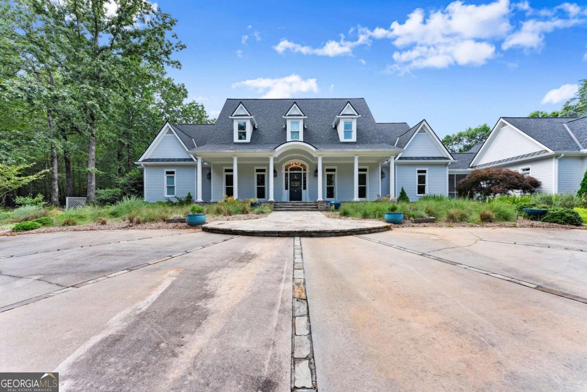 Perched on over 14 stunning acres, this breathtaking estate blends timeless elegance with unmatched tranquility in the heart of Dahlonega. Welcome to 77 Old River Road-a refined mountain retreat offering stunning views, total privacy, and a lifestyle of peace and sophistication. As you arrive, the stately driveway winds through professionally designed landscaping and leads to a grand Southern-style residence that captures the essence of North Georgia mountain living. Inside, the main level unfolds with warmth and elegance-featuring an open-concept layout, hardwood floors, soaring ceilings, and designer lighting. The expansive primary wing on the main floor includes a private fireplace, a newly updated spa-like bathroom, and access to a private deck with postcard-worthy views of the backyard oasis. A secondary ensuite bedroom, formal library/office, welcoming living room with fireplace, and gourmet kitchen with a breakfast nook and keeping room provide space for both relaxing and entertaining. Step out to the screened porch or enjoy the tranquil koi pond below-this is serenity redefined. Upstairs, discover a second luxurious primary suite, with custom cabinetry, additional guest bedrooms with flexible space for hobbies or work, and a cozy bonus room that could function as another office, or movie theater. Downstairs, the fully finished terrace level is an entertainer's dream, second family room, bonus space perfect for a theater, gym, or game room, and walk-out access to the outdoors. Outdoors, custom-crafted railings line peaceful walking paths, and multiple porches and decks invite gatherings under the stars. The estate includes ample parking with the three car garage and no HOA restrictions-offering freedom and comfort, just minutes from Downtown Dahlonega. Recently renovated with high-end finishes and featuring dual primary suites, this rare gem is perfect for those seeking luxury, privacy, and the magic of mountain living.