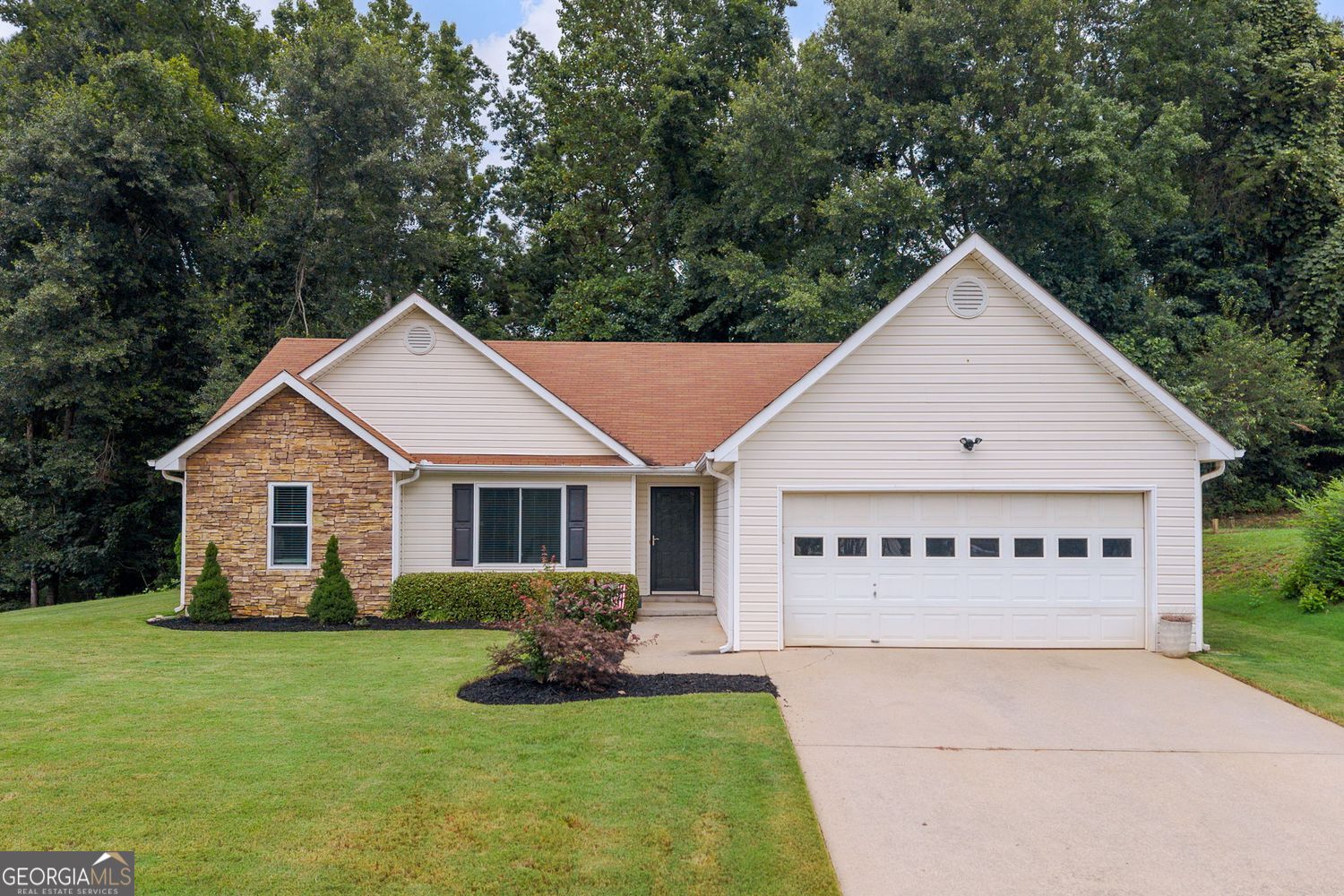 Fantastic opportunity for a beautifully renovated ranch home situated on a private, level homesite. This stepless, one-level gem blends comfort, style, and convenience with thoughtful upgrades throughout. Step inside to discover an airy open-concept living space featuring vaulted ceilings, a cozy fireplace, and wide-plank flooring that flows seamlessly through the main living areas. The fireside living room is the heart of the home and the perfect place to relax or entertain guests, flowing effortlessly into the bright and airy dining area and well-appointed kitchen. White cabinetry, granite countertops, stainless steel appliances, and charming farmhouse lighting elevate the kitchen, while a picturesque window in the breakfast nook frames a peaceful backyard view. The spacious primary suite on the main level is a true retreat, complete with a custom wood accent wall, tray ceiling, generous closet space, and a stunningly remodeled ensuite bath featuring dual vanities, a freestanding soaking tub, an oversized frameless glass shower, and designer tile. Two additional guest bedrooms share a full bath, offering ample space for family, guests, or a home office, all freshly updated and move-in ready. Out back, enjoy your private fenced yard with a pergola-covered patio, perfect for outdoor dining or relaxing in the shade, with plenty of green space for pets or play. Additional highlights include a dedicated laundry room, two-car garage, and recent upgrades that offer peace of mind from day one. Located in a swim/play community, residents enjoy access to a neighborhood pool and playground just seconds from the home. Conveniently located minutes from I-985, Lake Lanier, shopping, retail, and top-rated schools, this one checks all the boxes. Don't miss your chance to call this home!