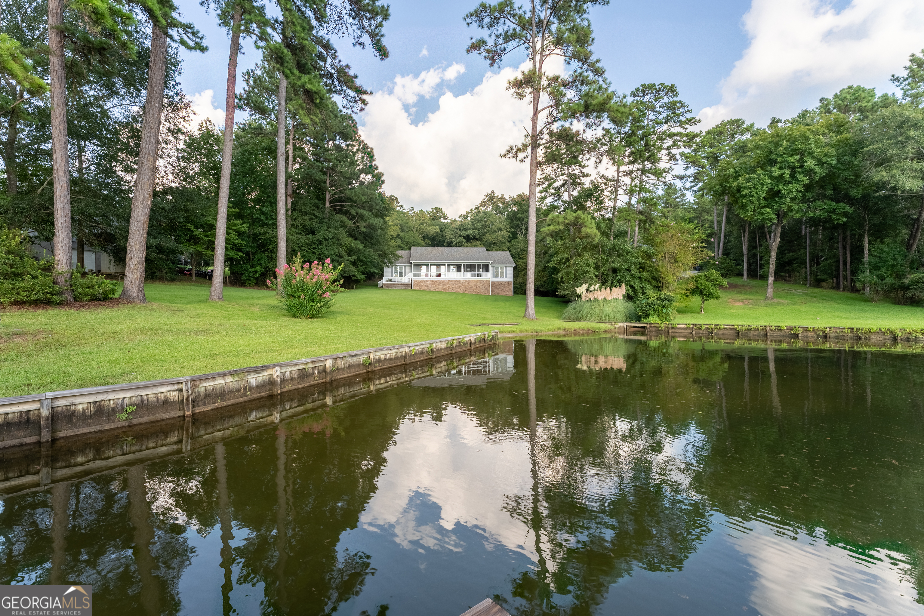 Discover your own private haven on 2.7 wooded acres with 240 feet of shoreline on lake Sinclair's coveted Rocky Creek Branch. Just 15 minutes from downtown Milledgeville, this point lot offers unmatched privacy, open-water views, and a perfect blend of lake life and convenience. Step outside and enjoy clear, deep-water ideal for swimming, boating and water sports. Your dock sits on 5 feet of water depth with boat lift and jet ski lift. Inside the 1 story ranch home you are welcomed with a split bedroom design. All rooms designed to capture the sweeping lake views from nearly every room. The partially screened front porch is perfect for morning coffee while enjoying Lake Sinclair. The stand-up crawl space offers exceptional storage, and the home is designed with peace of mind with its own well, whole house generator, and high-speed fiber internet. Facing west, this home gifts you with breathtaking sunsets every evening. this isn't just a house; it's a self-sufficient waterfront sanctuary offering privacy, security and a lifestyle only Lake Sinclair can deliver. Don't miss this rare opportunity, schedule your private showing today and experience the beauty of Rocky Creek living.