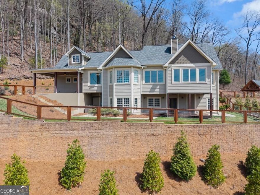 Nestled amidst the serene splendor of Tiger Mountain, this breathtaking 9-acre homestead seamlessly blends natural beauty with refined luxury. Located just 90 minutes from the heart of Atlanta and 12 minutes from the shores of Lake Burton and the charming town of Clayton, this property offers the perfect balance of accessibility and tranquil retreat. Perched high up the mountain the homestead boasts uninterrupted, panoramic views of pristine wilderness, facing expansive land managed by the US Forest Service-ensuring a timeless sanctuary with little chance of future development. Surrounded by towering hardwoods and the gentle whispers of nature this estate invites you to unwind and reconnect. The sprawling acreage provides endless possibilities whether you envision private hiking trials, a thriving garden, or simply a haven of peace and privacy. At the heart of this retreat lies an outdoor oasis designed for unforgettable gatherings: a heated pool with attached jacuzzi and cascading waterfall, a fully equipped outdoor kitchen, and a cozy fire pit area. All are crafted to elevate entertaining to a luxurious art form. Imagine hosting family and friends under the open sky, with ample space to invite then all- these amenities promise cherished memories filled with laughter, warmth and relaxation. The multilevel, Craftsman style, main house and accompanying pool house offer 8 spacious bedrooms, 8 full and 3 half bathrooms ensuring comfort and privacy for every guest. Enter the beautiful alder wood front door to discover rich hardwood floors that flow throughout. Ten-foot ceilings and eight-foot doors create an airy, expansive ambiance in every room. Adding to the allure are two stone fireplaces for those cool evenings. The owner's suite elevates luxury further with a spa-inspired bathroom featuring marble tile and a beautiful soaking tub room with a view overlooking the mountains. Convenience meets indulgence with two full kitchens, two additional kitchenettes, four laundry areas and a rejuvenating indoor sauna.  Every detail has been thoughtfully designed to make life effortlessly enjoyable whether you're preparing a feast, unwinding after a day of mountain or nearby lake adventures or simply soaking in the serenity. From the crisp mountain air to the star-filled skies, this Tiger Mountain gem promises a lifestyle defined by natural wonder, boundless possibilities and the ultimate in sophisticated comfort. Imagine the memories waiting to be made in a place where luxury and nature unite in perfect harmony.