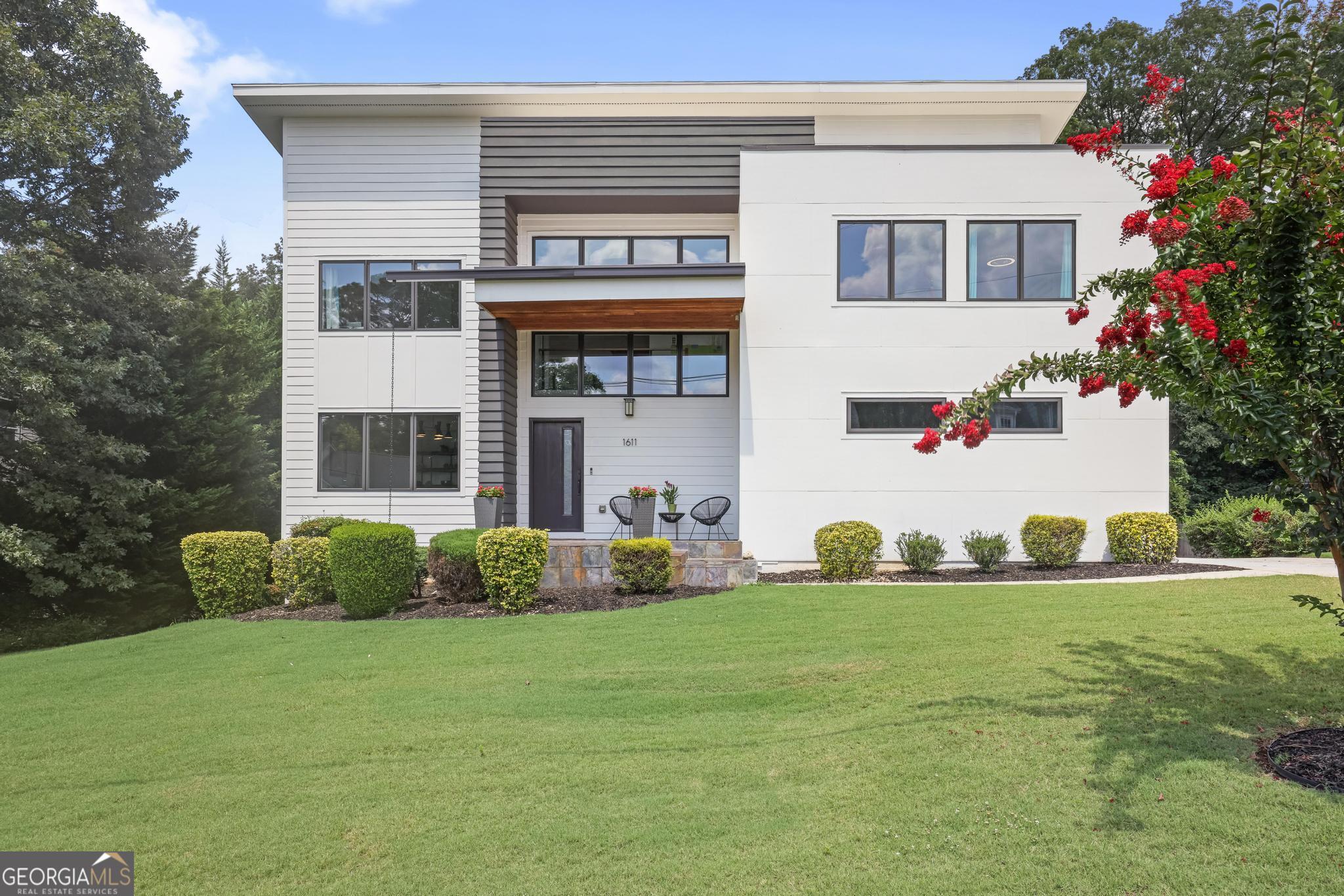 Discover a stunning California Contemporary masterpiece located in the vibrant heart of Smyrna! This 6-bedroom, 4-full bath home is a true gem in the Estates at Ellis Wade, perfectly positioned just a short stroll from The Silver Comet, Publix, Sprouts, and a variety of delightful restaurants. The moment you step inside, you'll be welcomed by an eclectic design in the dramatic two-story foyer, adorned with one of three circular ceilings and contemporary lighting. The exposed beams not only serve a functional purpose but also add a captivating aesthetic rarely found in other homes. The main level boasts an open floor plan where a light-filled, renovated kitchen seamlessly flows into the expansive two-story family room. Bathed in natural light from the massive windows and glass doors leading to a spacious deck, you'll revel in the serene views of the wooded backyard. The kitchen is outfitted with a chic new backsplash, a Bosch dishwasher, and sleek quartz countertops. Adjacent to the kitchen, you'll find a guest room, a full bath, and a separate dining room-ideal for hosting gatherings. Ascending to the upper level, the oversized primary suite awaits, complete with a tranquil deck for ultimate relaxation. The walk-in closet is enhanced with a custom California Closet system, offering effortless organization and ample space. In addition to the primary suite, three more luminous bedrooms, a full bath, and a dedicated laundry room complete the upper floor. The generous-sized finished daylight basement is an entertainer's dream, featuring glass doors that open to the covered patio and flat backyard. The deck is thoughtfully designed with underdecking, allowing you to enjoy the outdoors while remaining sheltered from the sun and rain. The finished basement also includes a large walk-in storage closet and an additional storage room, providing abundant space. This distinguished custom-built home is flooded with natural light on all three levels! Enjoy unparalleled access to Truist Park, The Battery, Vinings Jubilee, West Village, Cumberland Mall, Downtown, I-285, and Hartsfield International Airport, making it a prime location for both convenience and entertainment.