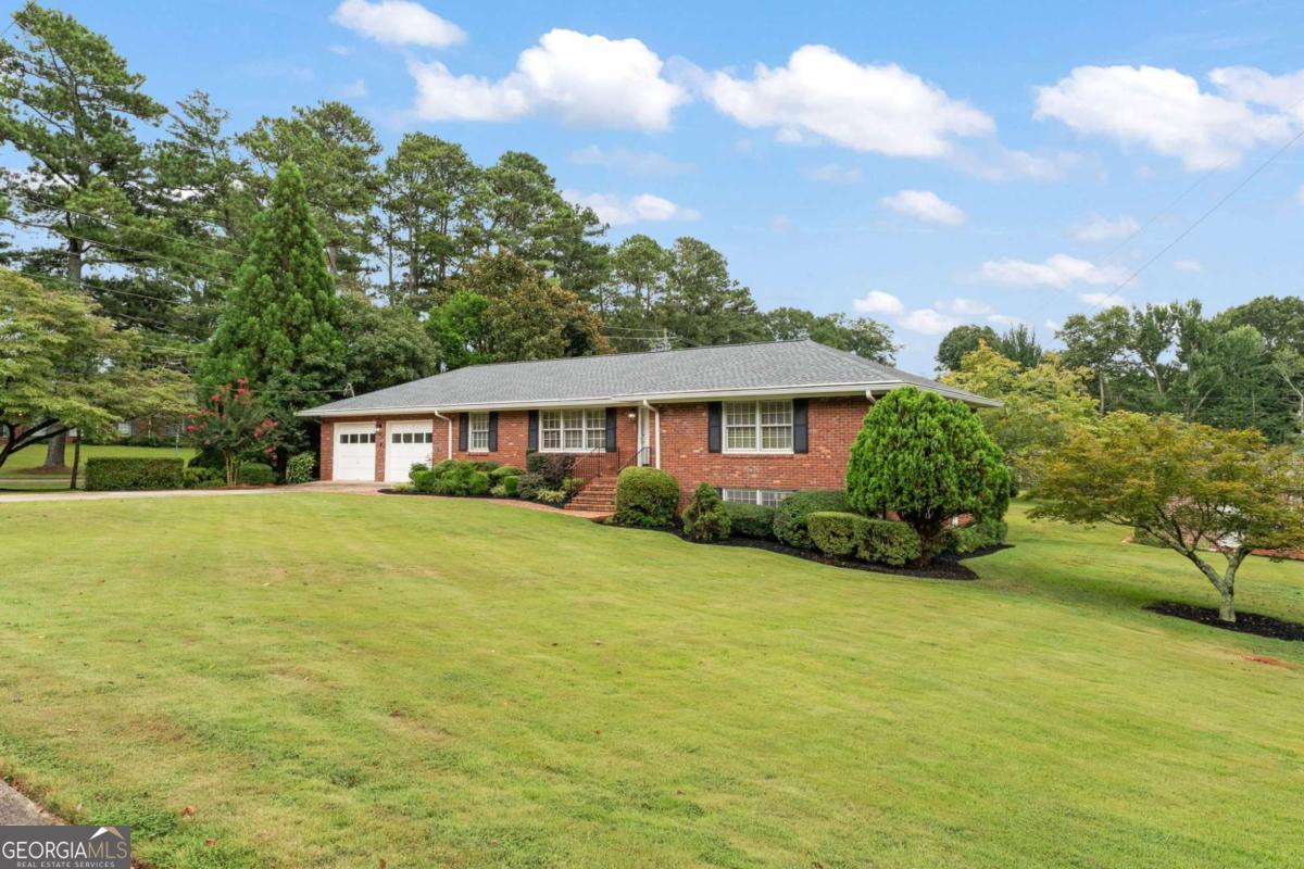 Charming 4-Sided Brick Ranch, 2-Car Garage, with a full daylight basement on this lovely spacious corner lot. Come see this beautiful 3-bedroom, 2-full bath home located in the most highly desirable Whitlock Heights Subdivision. You are approximately 8 minutes from near Historic Marietta Square. This handsome ranch home is ideally located in a well-established Marietta neighborhood with multiple points of entry and exit, to make commuting more pleasant. It's within walking distance of Hickory Hills Elementary School and Tumlin Park. This house has brand new architectural shingle roof installed in 2024 with a transferable warranty covering manufacturer's defects and workmanship. The Air Conditioner was installed in July 2025 with a transferable warranty. New recessed lighting and ceiling fans throughout. Hardwood floors run throughout the home. Tile runs through the lovely, updated kitchen with eat-in kitchen that includes ample cabinetry extending into a spacious laundry room. Kitchen has all modern updated appliances with under counter lighting and granite countertops. Enjoy breakfast in the eat-in kitchen or out on the large screened-in back deck while overlooking the huge backyard and established landscaping. The large living room can be a living and dining room combo. Spacious den/keeping room has a beautiful brick fireplace with newly installed hardwood floors. Three large bedrooms, living room, dining room on the main level all have original hardwood flooring. Fresh paint throughout the house, including the basement, 2-car garage, newly installed deck, screened porch, and exterior. Downstairs is an unfinished daylight basement with a second brick fireplace which is a blank canvas for additional living space or storage. This is a well-loved home that features an additional 1-car garage/outbuilding featuring a garage door and side entry, also with a new roof installed in 2024. The location of this home makes it easy to see why this neighborhood has stood the test of time with easy access to the vibrant shops, restaurants, and events of the conveniently located approximately 2.2 miles to beautiful Historic Marietta Square.