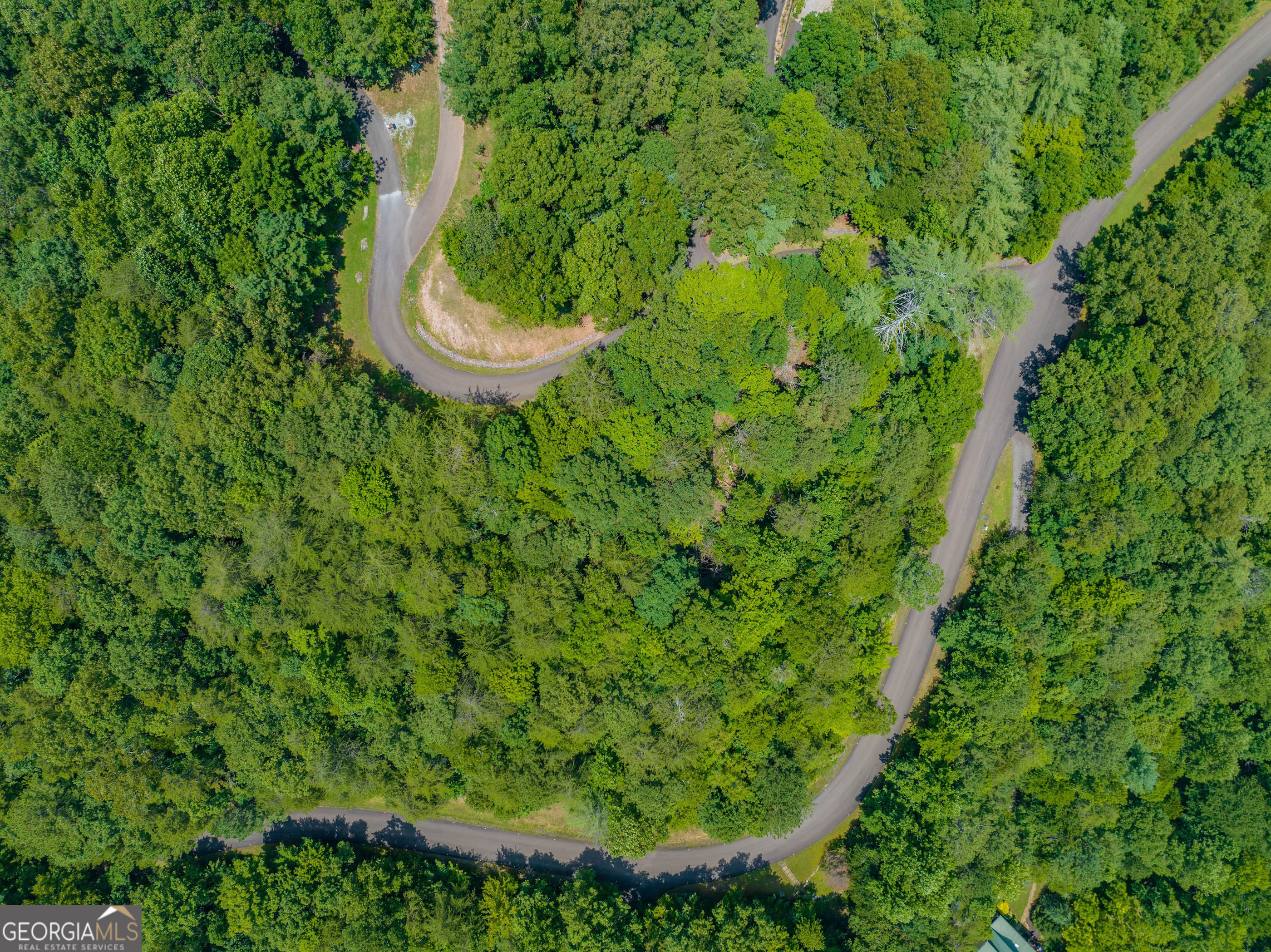Welcome to an exceptional opportunity to own 4.7 wooded acres in the prestigious gated community of Mountain Creek Hollow, nestled in the scenic foothills of the North Georgia Mountains. This unique property combines two adjacent parcels, one 3.08 acres and the other 1.62 acres, creating an expansive homesite with endless possibilities for your dream retreat. With paved road frontage on both the upper and lower sides, the property offers excellent accessibility and flexibility for building. The terrain features a mix of gentle, buildable areas and natural wooded privacy, giving you the perfect balance of charm and functionality. A Level 3 soil test has already been completed on one of the lots, saving you valuable time and providing peace of mind as you plan your future home. Mountain Creek Hollow spans approximately 275 acres of rolling, forested land, thoughtfully designed to preserve its natural beauty while offering residents a wide range of amenities. Within the community, you'll find a stocked trout pond, a butterfly garden, scenic hiking trails, and a picturesque covered bridge. A charming water wheel and small pond add to the rustic mountain atmosphere, while a neighborhood pavilion and picnic area overlook rushing Fausett Creek and its waterfalls. A community garden and paved walking trail provide even more opportunities to enjoy the outdoors and connect with neighbors. Ideally situated between Ellijay and Jasper, this location allows you to enjoy peaceful mountain living while still being close to local wineries, restaurants, shops, and entertainment. Please note that short-term rentals are not permitted in Mountain Creek Hollow, ensuring a serene and stable neighborhood atmosphere. This is a rare opportunity to secure a combined 4.7-acre property in one of Gilmer County's most desirable gated communities, offering the perfect setting for your custom-built mountain dream home.