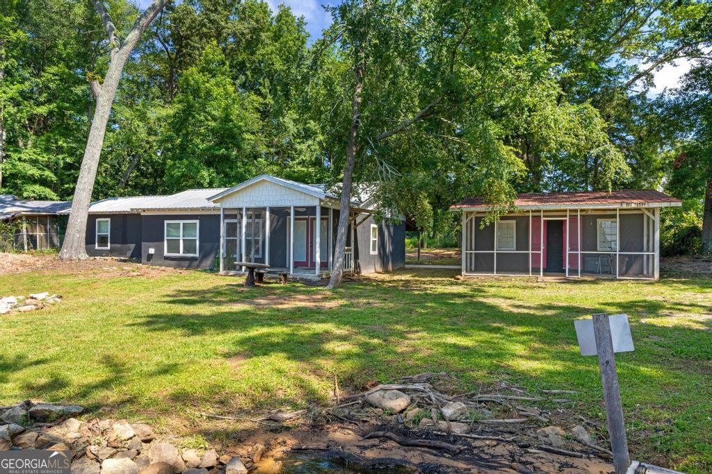 Charming Lakefront Retreat on a Deeded Level Lot with 100 Foot of Water Frontage! Welcome to your perfect lake getaway! This deeded lakefront property offers 2 bedrooms and 1.5 bathrooms on a level lot just steps from the water. No steep hills here! Enjoy stunning lake views from your open-concept kitchen, dining and family room, all freshly updated with brand-new carpet. Step outside to relax on the screened patio, enjoy fishing off of your 25 foot dock or take advantage of the separate outdoor bunkhouse- ideal as a guest suite or storage for all your lake gear. Refresh and rinse off those sandy feet and sun-soaked smiles after a day on the lake in the rustic outdoor shower. Such a fun and convenient feature just steps from the lake. Located near Berry's Boat Dock, nestled in an inlet near the 212 Bridge, this property is a dream come true for lake lovers. Whether you're looking for a full-time residence or weekend retreat, this one is a must see! Adjoining property 10687 GA Highway 212 is also included in this sale.