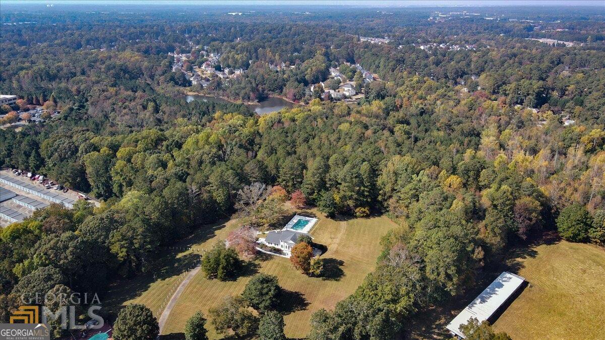 Discover Southern elegance in this antebellum-inspired estate on 11 level, usable acres. Built in 1964 and spanning approximately 5,484 sq ft, it features 7 bedrooms, 6 bathrooms, and a basement apartment for flexible living. Primary suite on main floor. Inside, enjoy hardwood floors, high ceilings, and abundant natural light. Outside, relax by the sparkling pool under majestic magnolias, enjoy the garden, or walk the trails. With 200 ft of highway frontage and three divisible lots (sewer installed on part), its mixed-use zoning allows for the perfect homestead property or commercial ventures like event hosting, short-term rentals (such as Airbnb for residential income), healthcare facilities, retail, offices, or even an equestrian estate leveraging its expansive acreage. near I-75 for easy access. Buyer to verify all zoning and lot lines.
