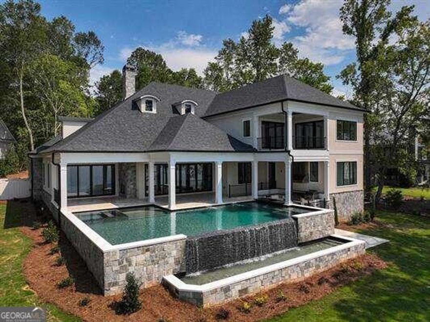 Lakefront Oasis with 255 feet of lake-frontage on Lake Oconee!! This stunning new construction in Reynolds at Great Waters was built with quality craftsmanship, unparalleled attention to detail, the finest selections and finishes, and boasts 6,750sqft of luxurious living space with 5 bedrooms, 5 full baths, 2 half baths, a two-story dining room, a two-story study, a lakefront entertainment/media room with a bar, a wine cellar with a tasting area, a flex room/gym, and a spectacular pool offering endless panoramic lake views!! Designed for entertaining, the open floor plan seamlessly flows from the spacious vaulted family room to the beautifully designed gourmet kitchen, and out to the infinity-edge pool. The main level is a sanctuary unto itself, with the owner's lakefront suite offering ultimate privacy, featuring a coffee station/mini-bar, two custom closets with a 2nd private laundry, two water closets, a gorgeous oversized walk-in shower, a garden tub, a towel warmer, and heated floors! Three additional guest suites are on the main level along with a chef's kitchen equipped with Wolf and SubZero appliances, a designer quartz-topped white oak island, a breakfast area with a wet bar, and a butler's pantry with a built-in Wolf coffee station. The main laundry is spacious with custom closets and will spoil you with an LG Steamer Closet. You can retreat to the second level of the home by elevator or the beautifully crafted double-wide staircase to find an additional lakefront guest suite, flex room/6th bedroom, designer wine cellar with Alder wood racks and 10' glass wall, a 2nd glass encased wine wall that is artistically exposed to the Great Room below, and a lakefront media room and bar with covered patio that provides the most gorgeous lake views and sunsets! The 40x18 salt-water pool has a swim-up bar with built-in stools, a dining table, a tanning ledge, a jacuzzi, two water features, and an outdoor kitchen with a grill and vent hood, side burner, pizza oven, and mini-fridge. In addition to all the attributes of this amazing home, the oversized 3-car garage with epoxy flooring is equipped with an electric car charging station. What more could you ask for? Come experience luxury living at its finest in this exceptional home! Contact us today for your private tour. Golf Membership available.
