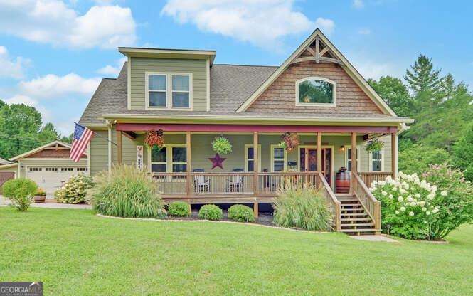 Tucked in a quiet community just minutes from Lake Nottely, this Craftsman-style home blends timeless design with modern comfort. Inside, soaring wood ceilings and a stone fireplace set the tone for the open great room, while the farmhouse-inspired kitchen offers granite counters, stainless appliances, gas stove, and plenty of storage. The main-level primary suite is a private retreat with a clawfoot tub, oversized tiled shower, and walk-in closet. Upstairs, two guest bedrooms and a full bath provide room for family or friends. Outdoor living shines with a screened porch, custom timber-framed carport, and a detached two-car garage featuring a heated and cooled flex room-ideal for a home office or hobby space. With meticulous landscaping, RV hookup, and easy access to boat ramps, trails, and downtown Blairsville or Blue Ridge, this home is the perfect mix of relaxation and convenience. Additional property on each side of this home also available.