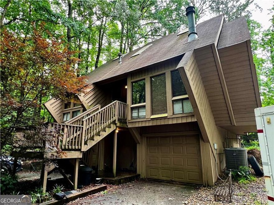 Calling all artists, visionaries, and lovers of the wonderfully unexpected-welcome to 2965 Pond View Ct, a truly unique contemporary diamond (literally!) in East Cobb. This is no cookie-cutter house. Designed and built by Tom Mozen-a local builder known for his bold, architectural creativity and his motto of never building the same home twice-this was the very first neighborhood he developed in East Cobb. And he made sure to start with a statement.  From the moment you arrive, you'll notice the daring angles and striking shape of this diamond-shaped split-level home, tucked at the end of a quiet cul-de-sac on a private, wooded lot. Step inside and you're greeted with an architectural centerpiece: a spiral staircase suspended by cables, leading to a private primary suite perched above the rest of the home. This suite includes a full bathroom and opens to a covered deck overlooking the backyard-an ideal retreat to sip coffee, read, or create.  On the main level, you'll find two additional bedrooms and a full bath, with plenty of natural light and potential to update or reimagine. The unfinished lower level offers room to expand, with the potential for another bedroom, bath, studio, or media space. There's also a two-car garage, and the shared driveway adds a touch of old-school charm to this hidden enclave. Ideally located in the heart of East Cobb, this home is just a short walk to top-rated Pope High School and zoned for some of Cobb County's highest-performing public schools, with convenient access to shopping, dining, parks, and major highways like I-75 and GA-400-making everyday errands and commutes a breeze.  This home is being sold AS IS and is perfect for someone with vision, creativity, and an appreciation for bold design. It's not just a house-it's a conversation starter. If you've been searching for a fixer-upper with personality and serious architectural chops, this is the one.