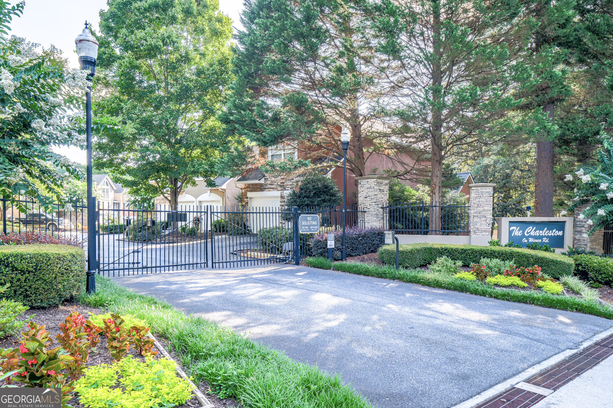 Lock & Leave. This hidden gem in the heart of North Buckhead lives like a large single family home. Tucked away in a quiet enclave of 18 homes, this rare 4-bedroom, 3.5-bath end-unit townhome offers an unbeatable combination of space, architectural elements, natural light, and location. A gated entrance leads you into a beautifully maintained home with a large house-like footprint spanning three spacious levels. Soaring ceilings, a dramatic two-story foyer, a wall of windows, and a unique atrium/patio flood the main level with natural light. The stunning 2-story living room features built-in bookshelves and a cozy fireplace, while the white eat-in kitchen offers ample storage and functionality. The oversized primary suite serves as a private retreat, thoughtfully separated from two additional guest bedrooms and a full bath down a sunlit hallway. The fully finished terrace level includes an additional bedroom and bath-perfect for an in-law suite or home office-along with generous storage space. Additional highlights include a main level two-car garage, plenty of guest parking, sky-high ceilings in the main living area, FEE SIMPLE ownership, low HOA dues (which include weekly yard blowing), and true lock-and-leave convenience. Located just minutes from Chastain Park and Blue Heron Nature Preserve and within walking distance to Publix, Fresh Market, Trader Joe's, and neighborhood favorites like Fellini's and La Fonda, this home offers easy living, top-rated schools, great neighbors, and proximity to some of Atlanta's best parks, shops, and dining. The square footage (which includes terrace level) for the price in the area is unmatched. These townhomes rarely hit the market - do not miss it.