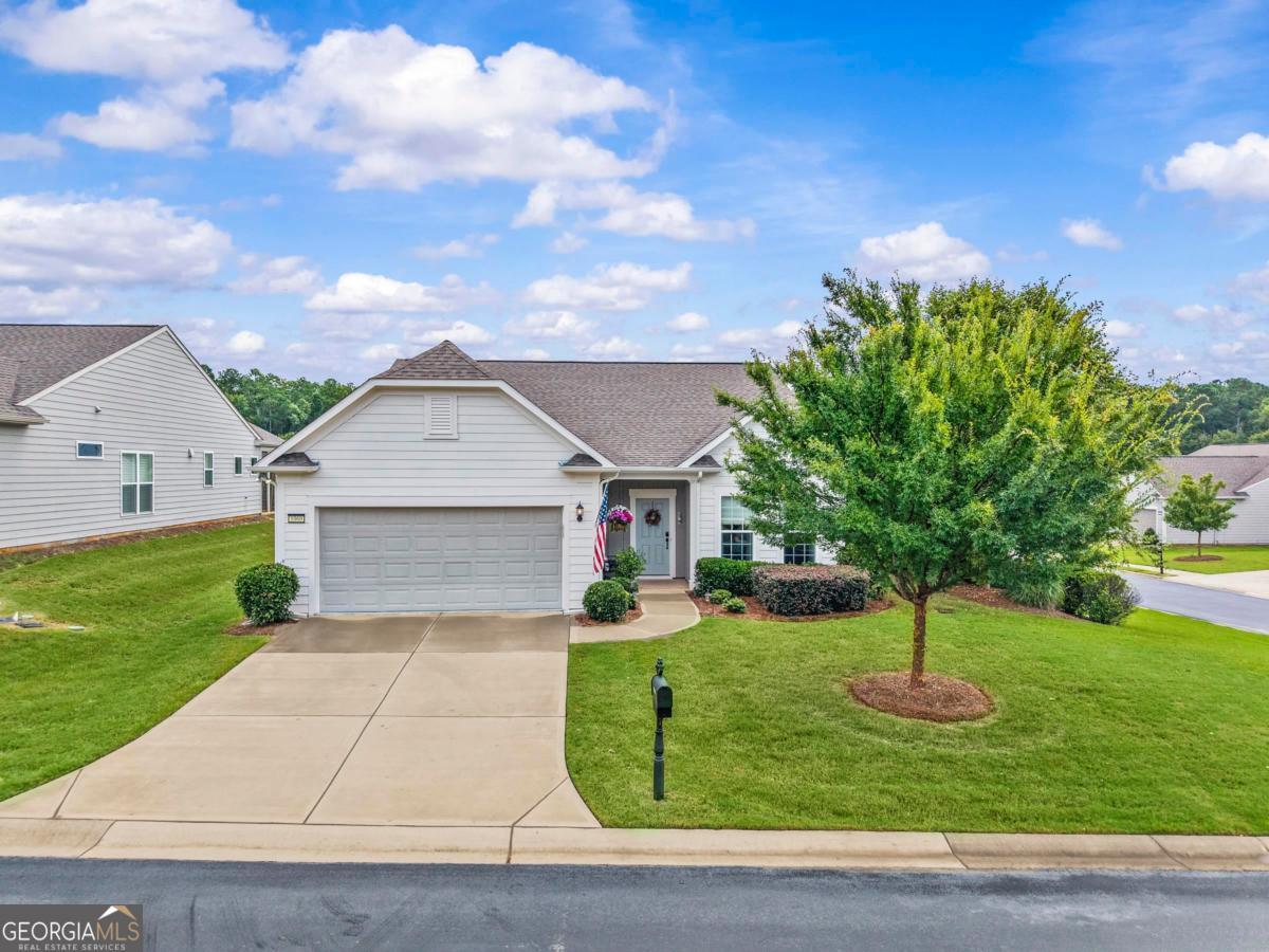 Perfectly positioned on a corner lot in Del Webb at Lake Oconee in the sought-after Hidden Cove community, this like-new Martin Ray-arguably the most desired floor plan in Del Webb-offers an outdoor sanctuary with lush shrubs, mature trees, and layered landscaping. The extended covered patio is surrounded by greenery and a gated backyard, creating a peaceful, garden-like retreat perfect for relaxing, gardening, or entertaining in privacy. Inside, the open layout offers a spacious gourmet kitchen featuring a large island with seating, white quartz countertops, upgraded cabinetry, stainless steel appliances, a custom and upgraded butler's pantry, and a walk-in pantry. The light-filled main living areas showcase wide-plank hardwood flooring, elevated lighting, and custom window treatments. French doors lead to a versatile office or flex space. The primary suite is a true retreat, featuring a spa-like bathroom with dual vanities, upgraded tile, and a generous walk-in closet. The second bedroom is spacious and adjacent to a full bath, making it ideal for guests. Additional highlights include a long tandem garage with space for a golf cart or workshop and utility sink, attic storage, a propane gas fireplace, and a water softener/filtration system with instant hot water. Enjoy the serenity of your own sanctuary in a tucked-away location along with all of Del Webb's resort-style amenities - including an indoor and outdoor pool, croquet, bocce ball, tennis, pickleball, a clubhouse, direct lake access with boat ramp, docks, boat storage, and more - plus a low-maintenance lifestyle that lets you enjoy it all.
